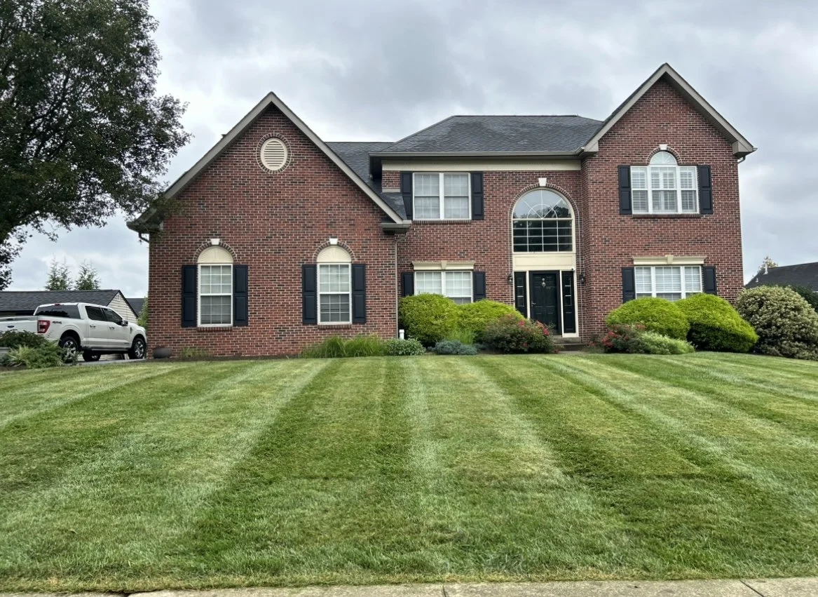 Brick house with manicured lawn and shrubs