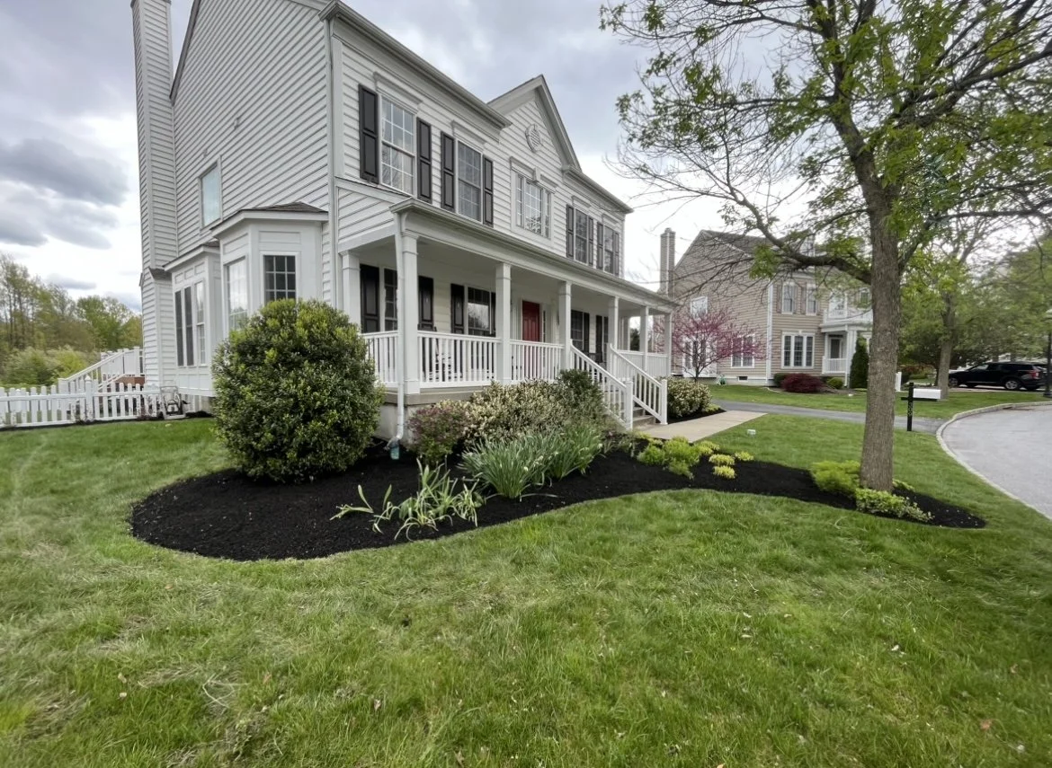 Suburban house with front porch, landscaped garden, and green lawn