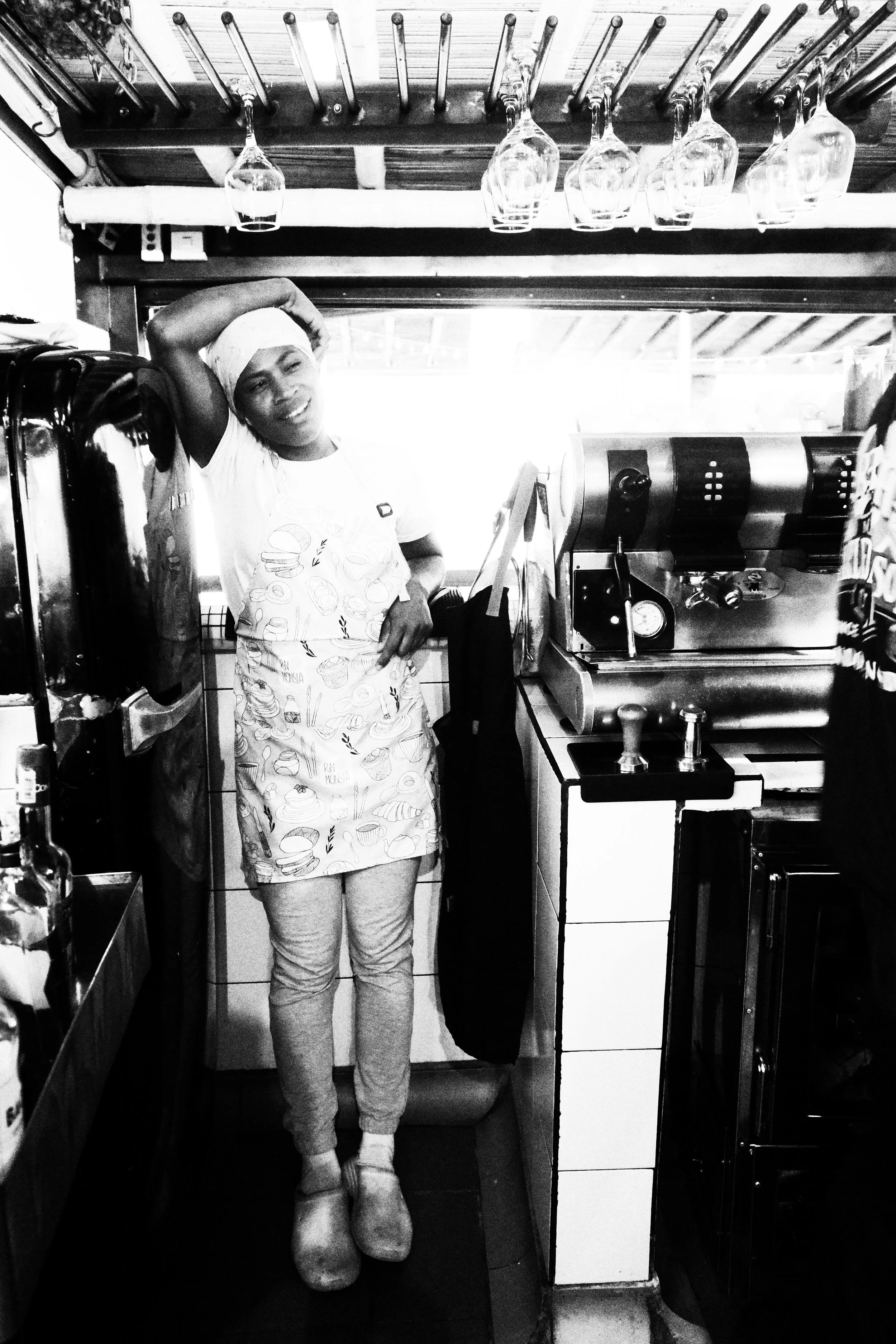 A black and white photo of a chef, with blurred figures and lights illuminating the background.
