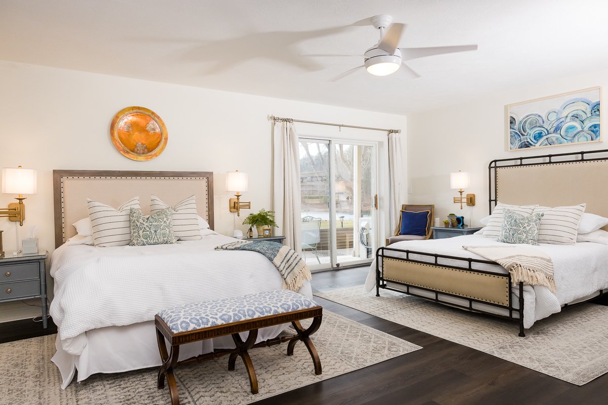 A bedroom with a queen bed in a vacation rental home in north Georgia. A white bed, cream backboard and a round platter over the bed.