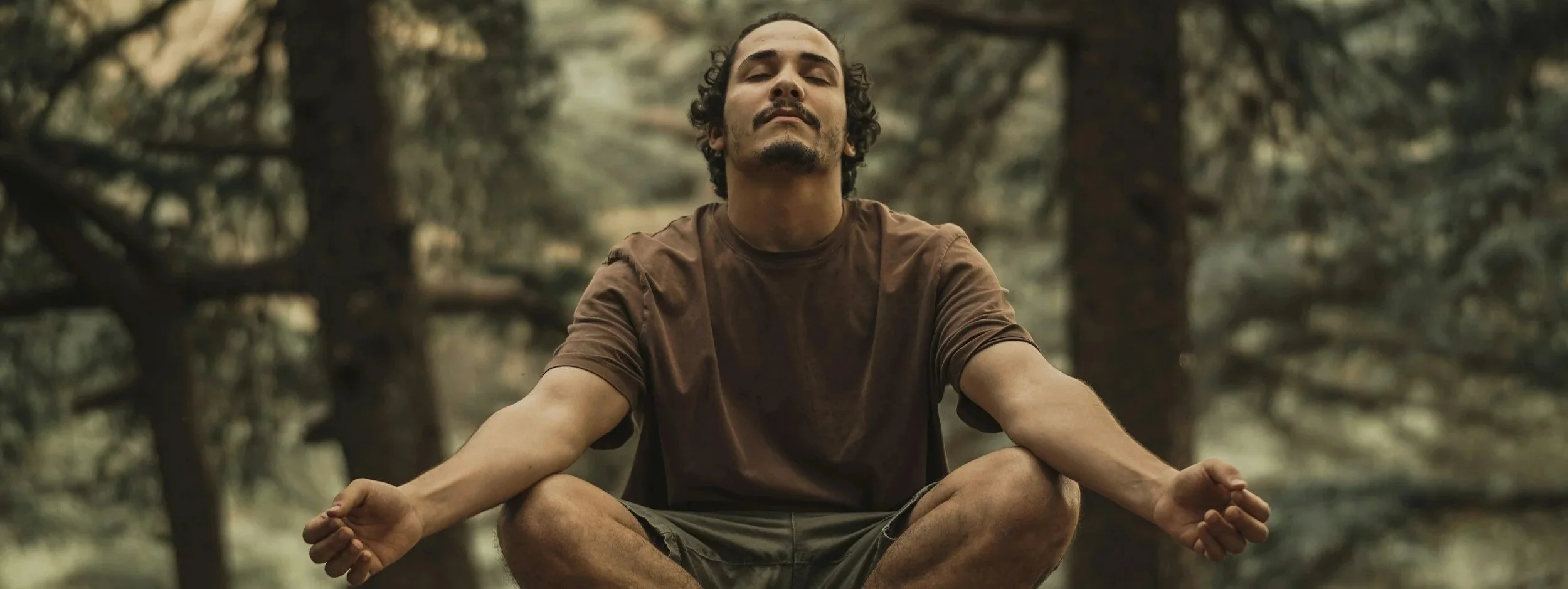 a man sitting crosslegged with his eyes closed and his arms resting on his knees, breathing