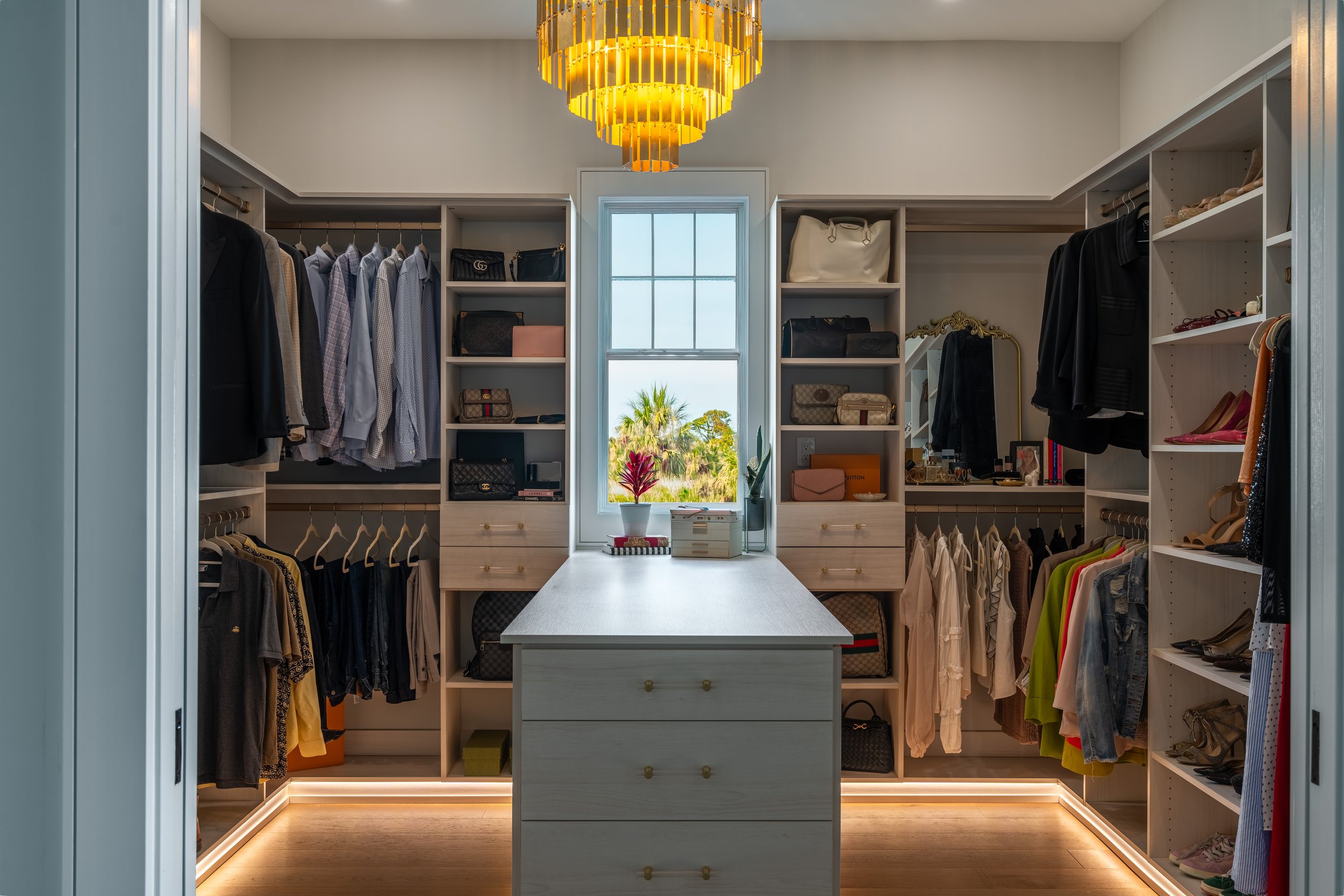 Luxury walk-in closet with center island, chandelier and LED lit shelving