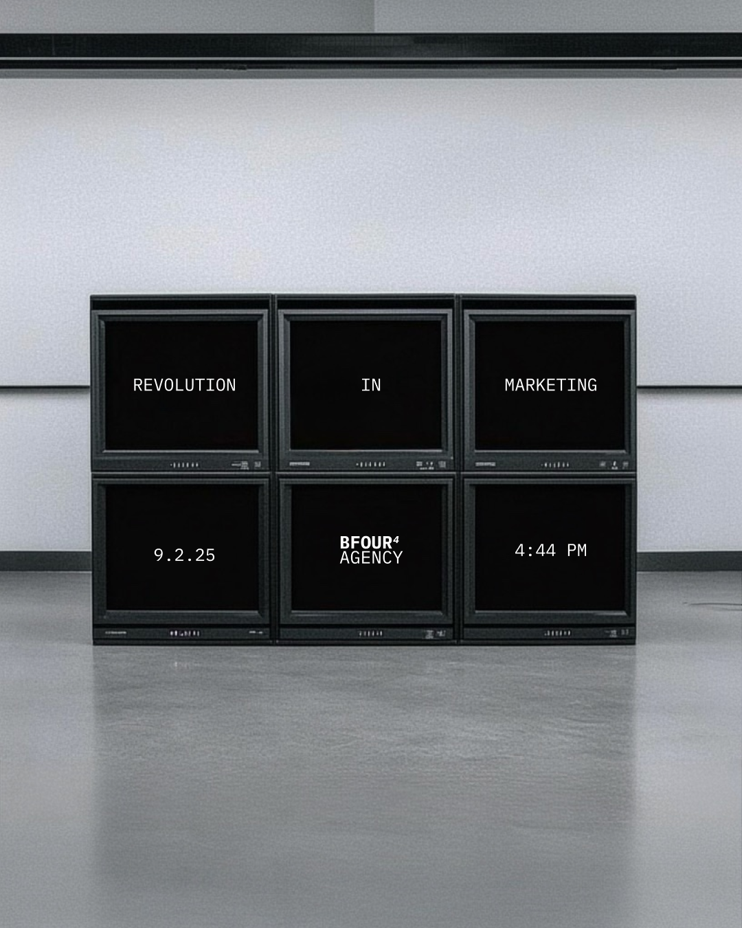 Six old computer monitors arranged in two rows on a gray floor against a gray wall. The screens display the message 'REVOLUTION IN MARKETING 9.2.25 BFOUR4 AGENCY 4:44 PM'.
