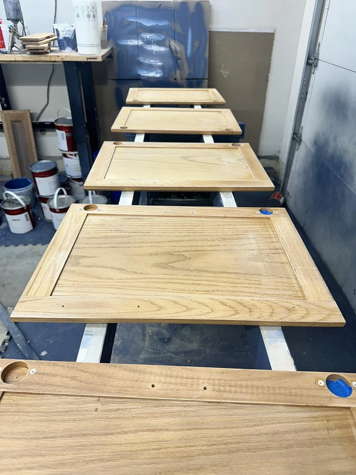 Oak cabinet doors sanded and prepped in workshop before priming and painting.