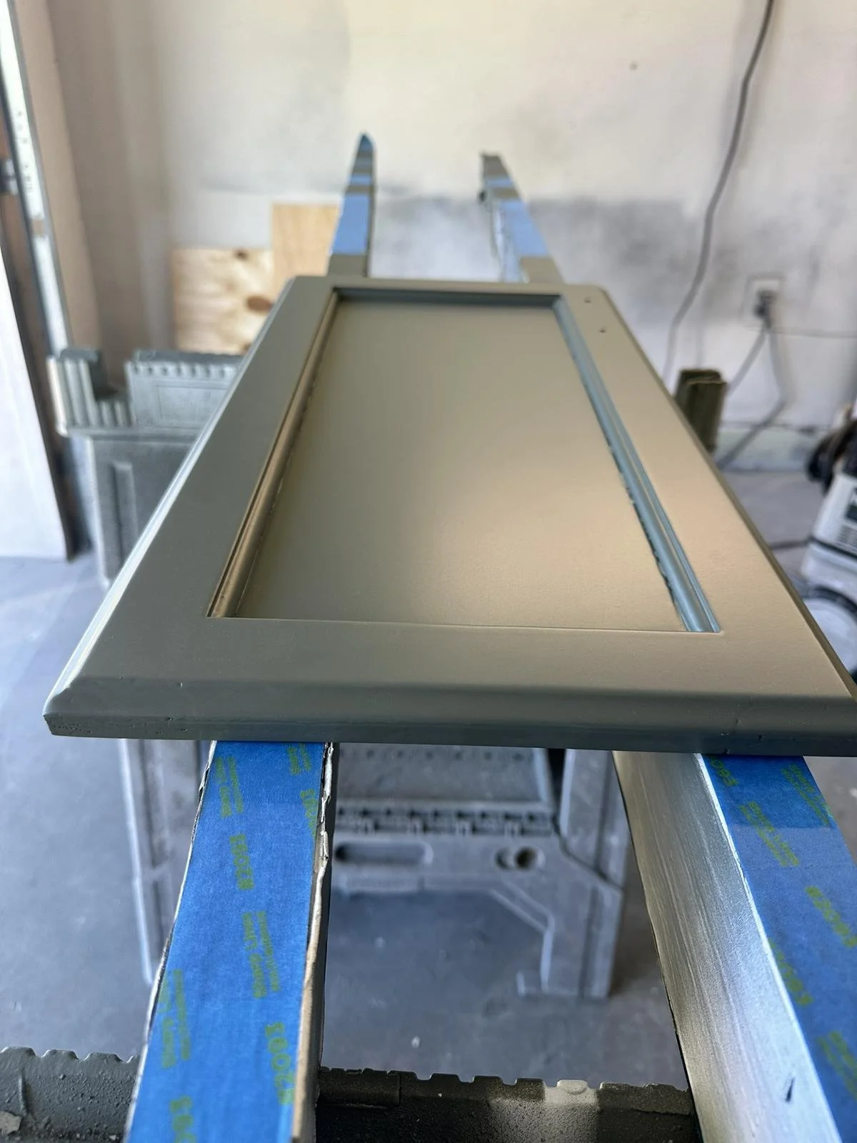 Close-up of refinished oak cabinet door in smooth gray finish after primer and paint.