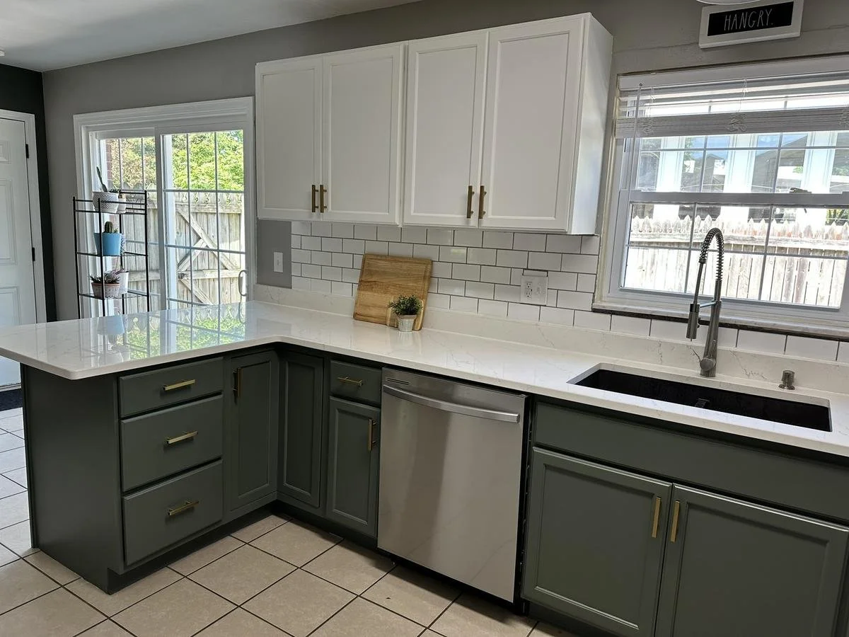 Close-up of refinished cabinets with sage green lowers and white uppers, accented with brass hardware.