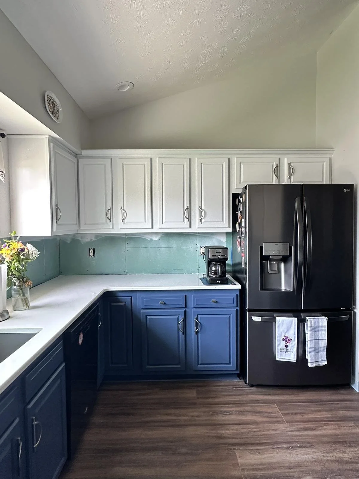 Kitchen with two-tone cabinets refinished in blue lowers and white uppers for modern style.