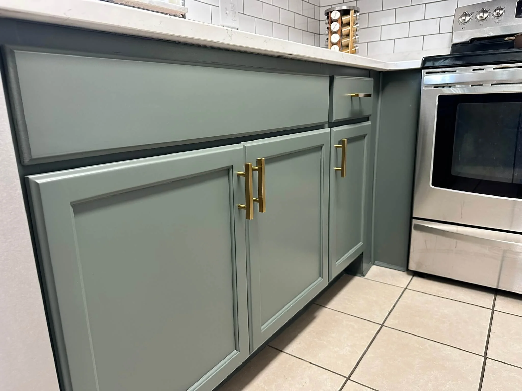 Smooth green kitchen cabinets with brass hardware in Dayton, OH