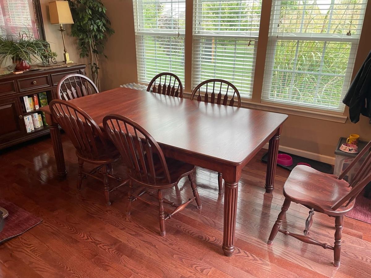 A refinished wooden dining table with six matching spindle-back chairs from Craft & Revive in Kettering, OH, set in a bright dining space.