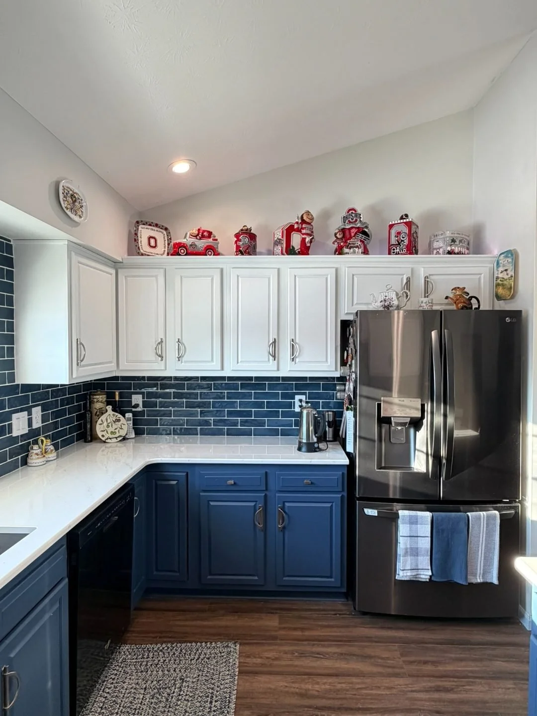 Two-tone kitchen cabinet refresh with white uppers and deep blue lowers, paired with a navy subway tile backsplash and stainless appliances.