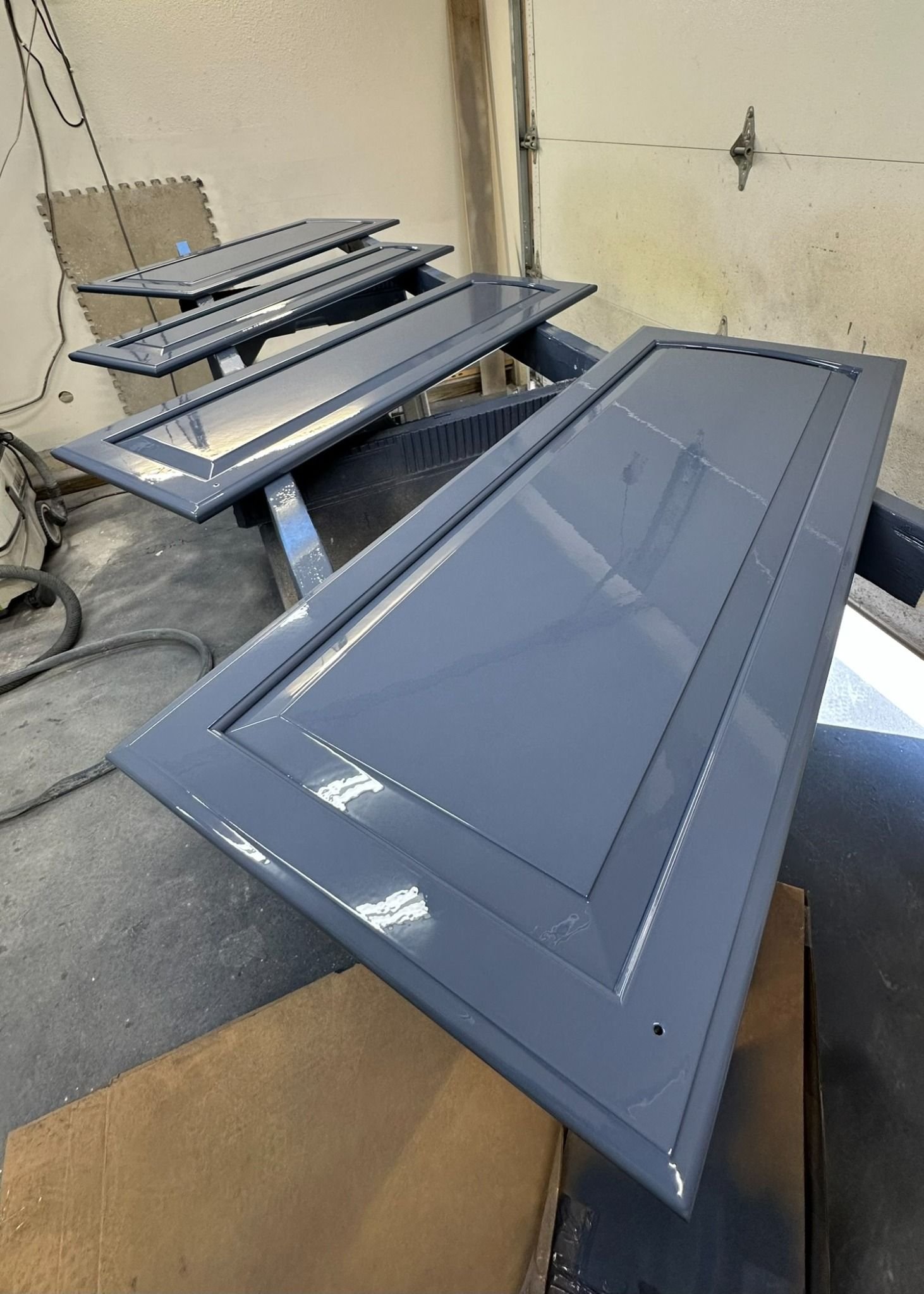 Navy blue cabinet doors refinished with a high-gloss finish by Craft & Revive in Dayton, OH, during a professional painting process.