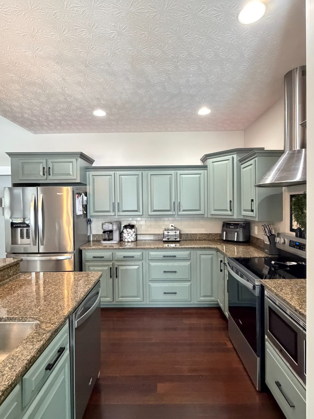 Two-tone kitchen with white upper cabinets, deep blue base cabinets, navy subway tile backsplash, and stainless steel refrigerator.