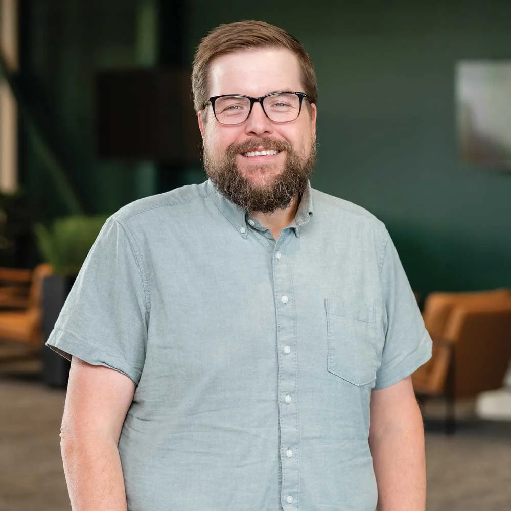 This is a picture of Brandon Rodgers. He's wearing a light gray button up shirt.