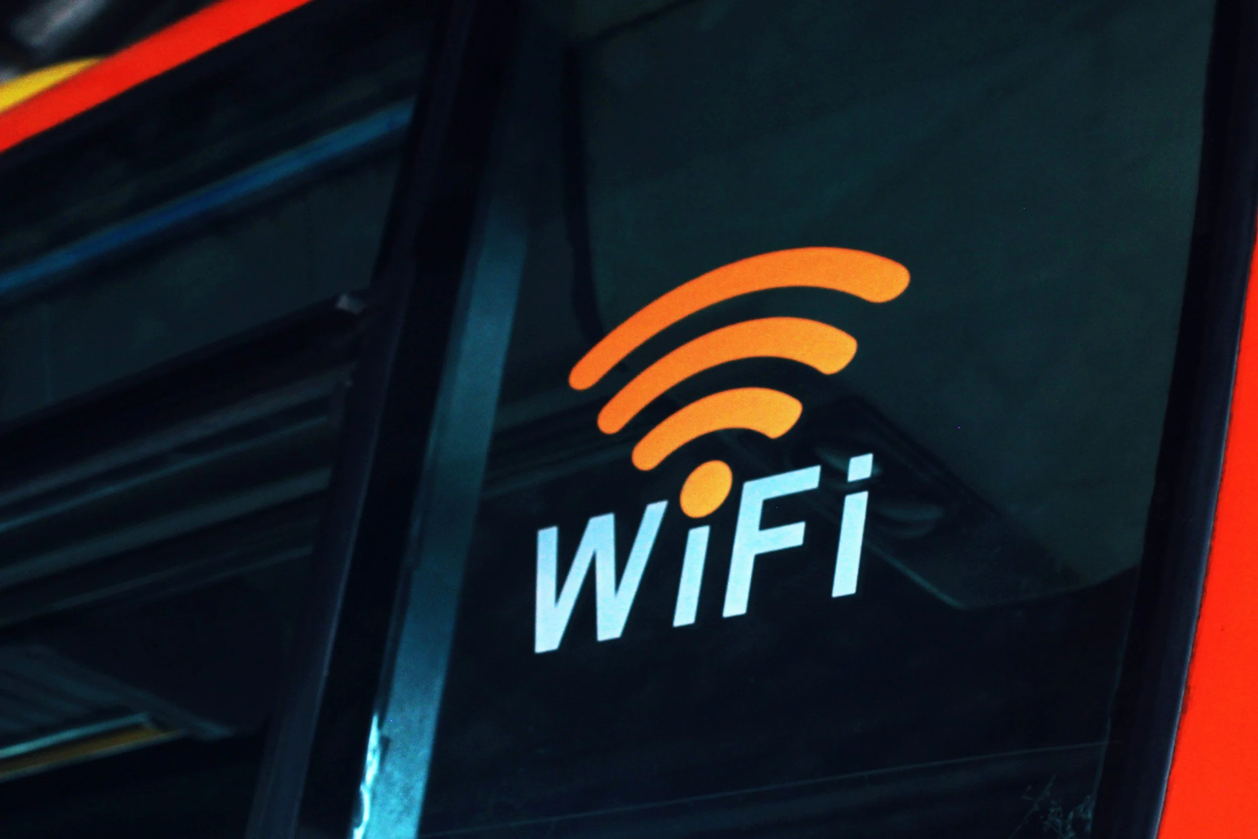 Wi-Fi sign on the exterior of a building with a Wi-Fi symbol in orange above the word 'WiFi' in white letters.