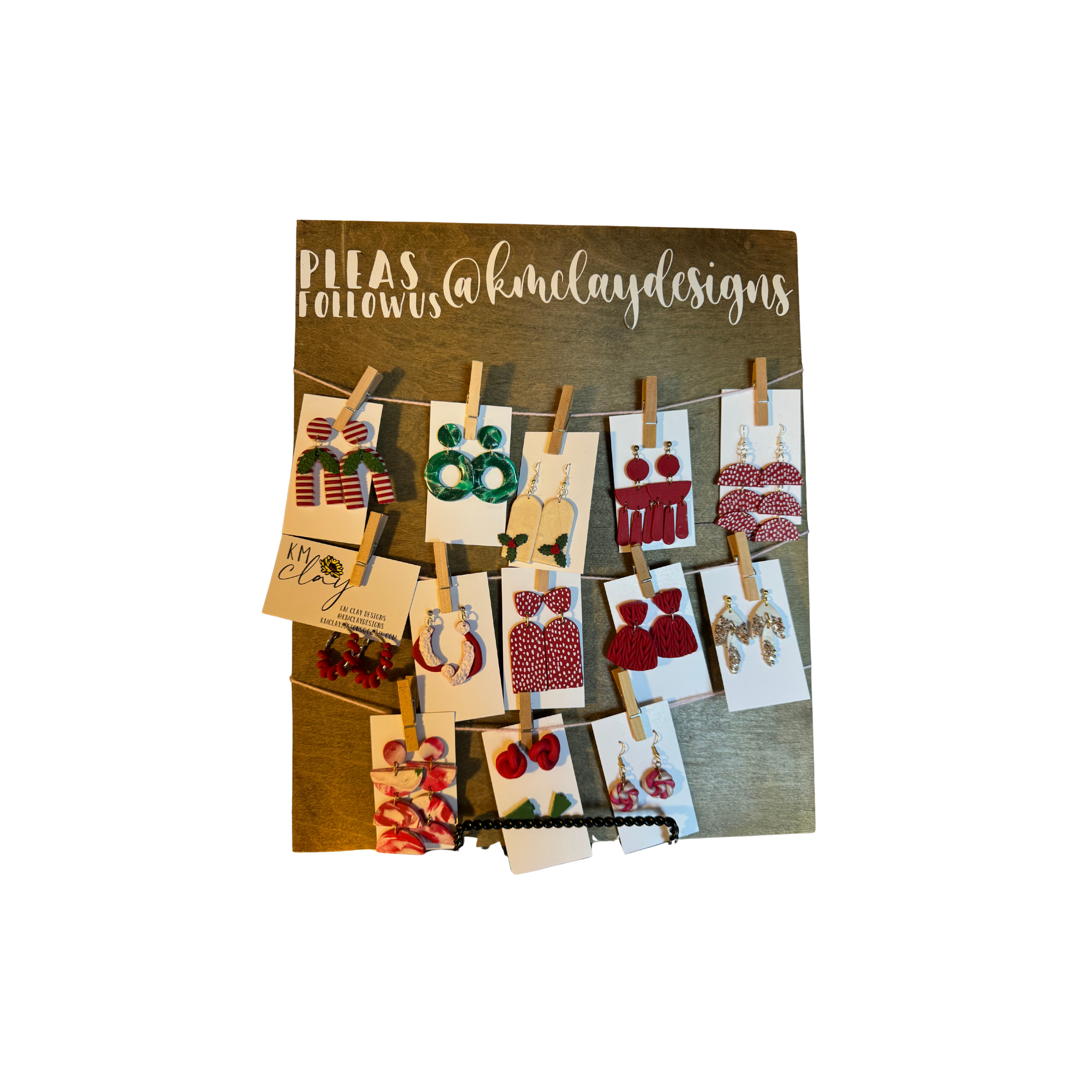 Display of various holiday-themed earrings hanging on a jewelry board, with a sign requesting follows on social media
