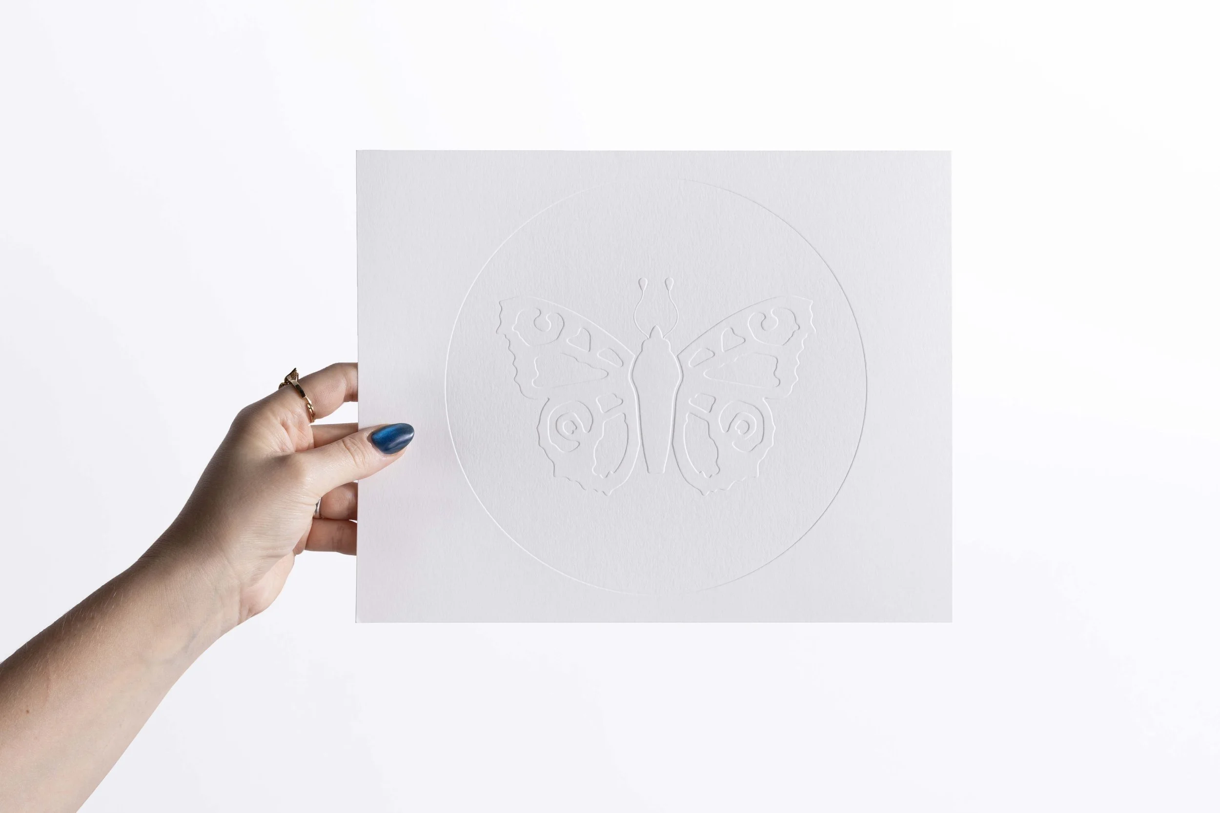 White embossed artwork featuring a circular composition with detailed butterfly illustrations at the center.