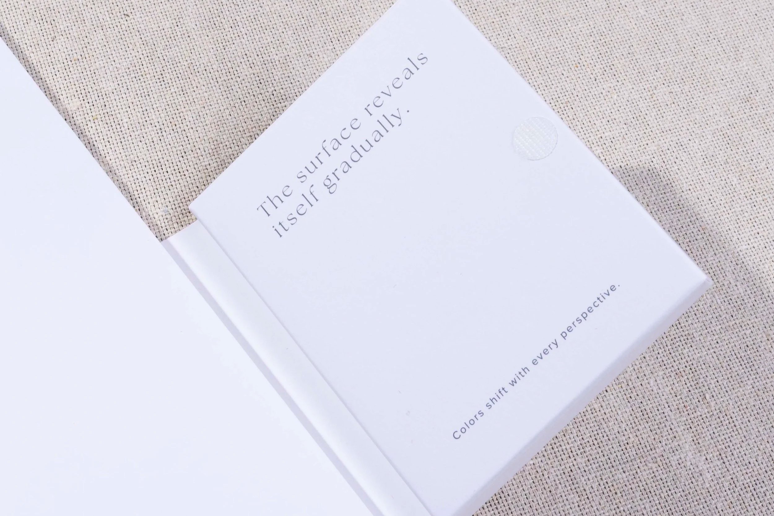 Close-up of the interior pocket that holds the watercolor card featuring the statement “The surface reveals itself gradually.”