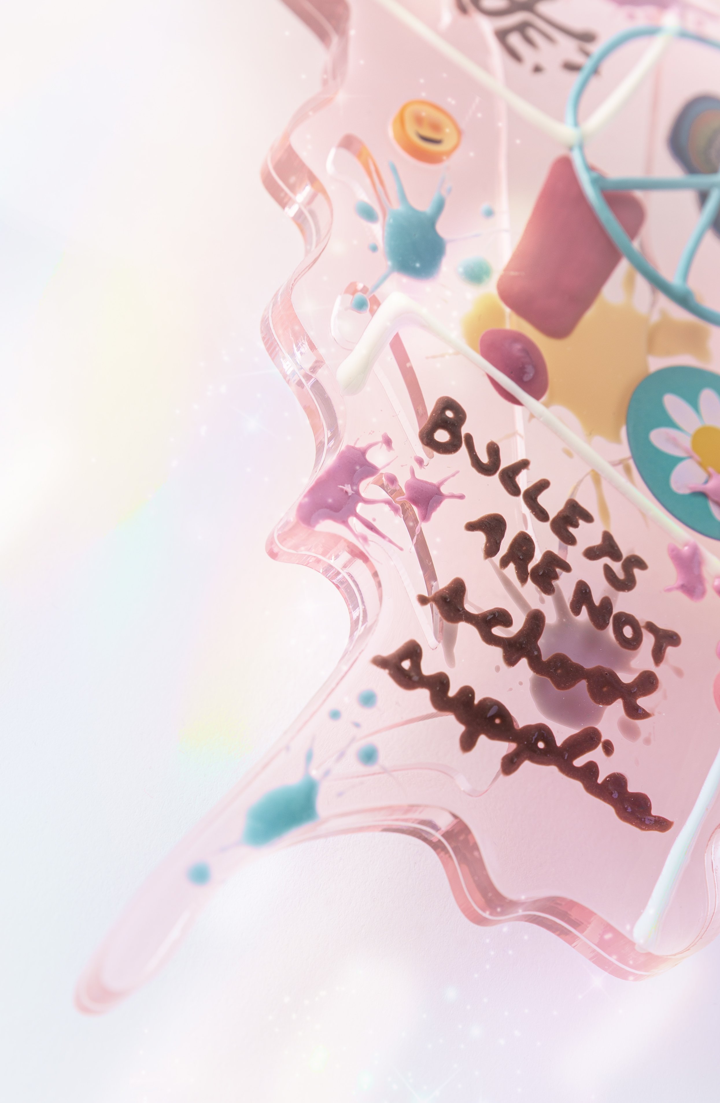 Close-up of a pink resin butterfly sculpture with handwritten text that says 'Bullets are not school supplies'.