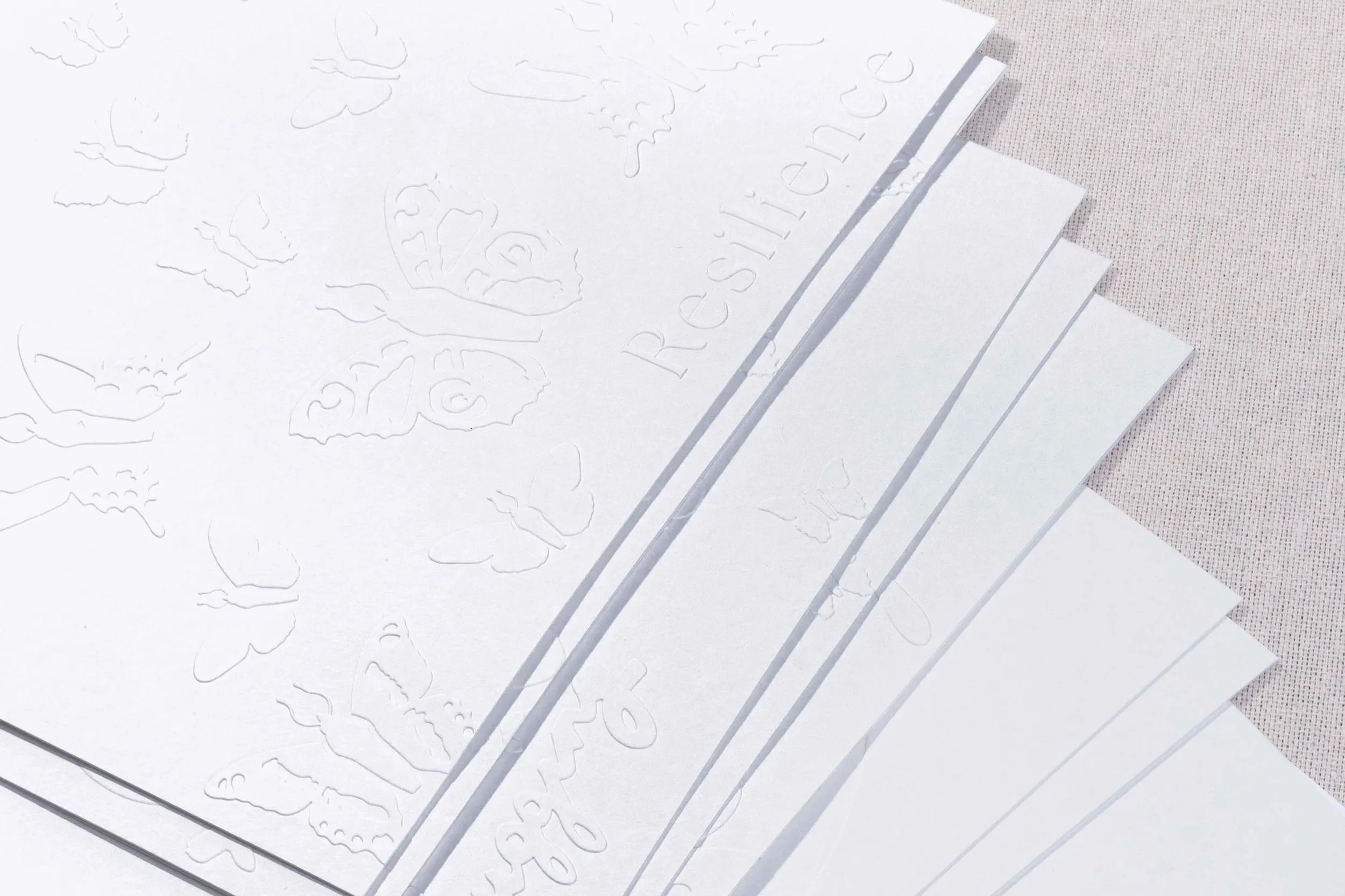 Close-up view of the embossed, Resilience watercolor pages showing embossed butterfly illustrations, typography, and layered page edges.