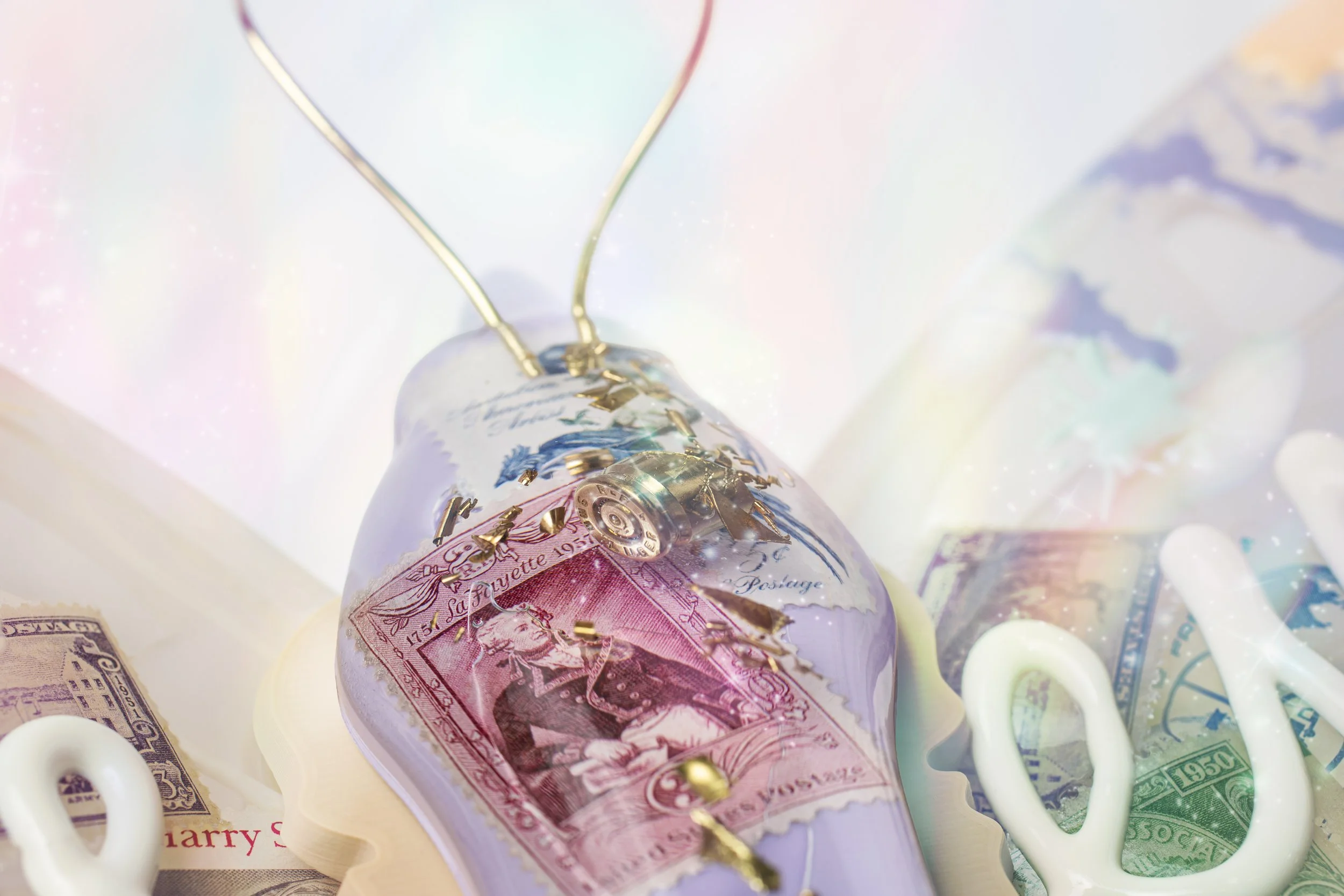 Close-up of a resin butterfly thorax with embedded bullet casings and vintage stamps.