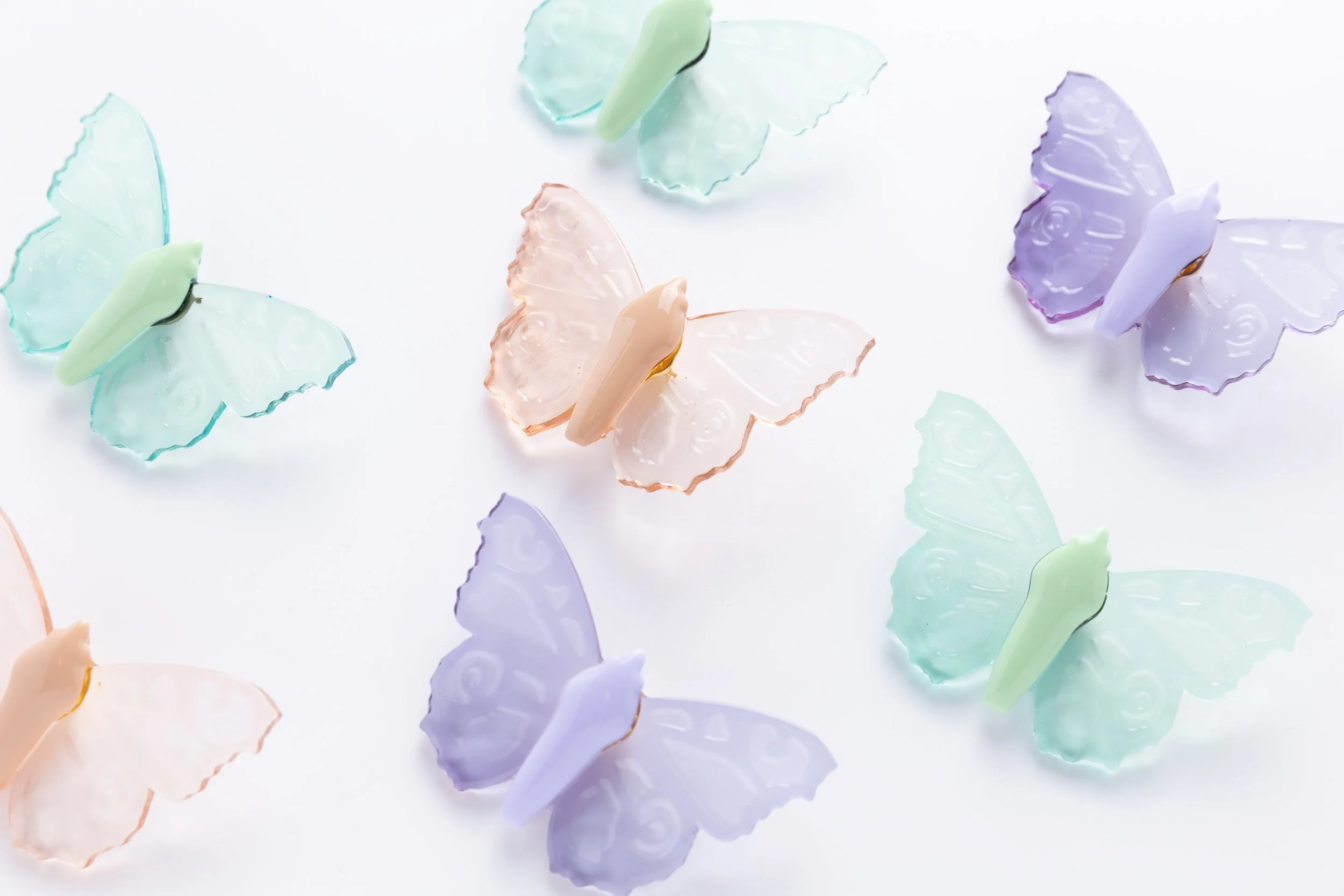 Colorful translucent soft resin butterfly pins in Twilight Glass, Sea Glass, and Desert Glass, handcrafted by Butterfly Art Collective.