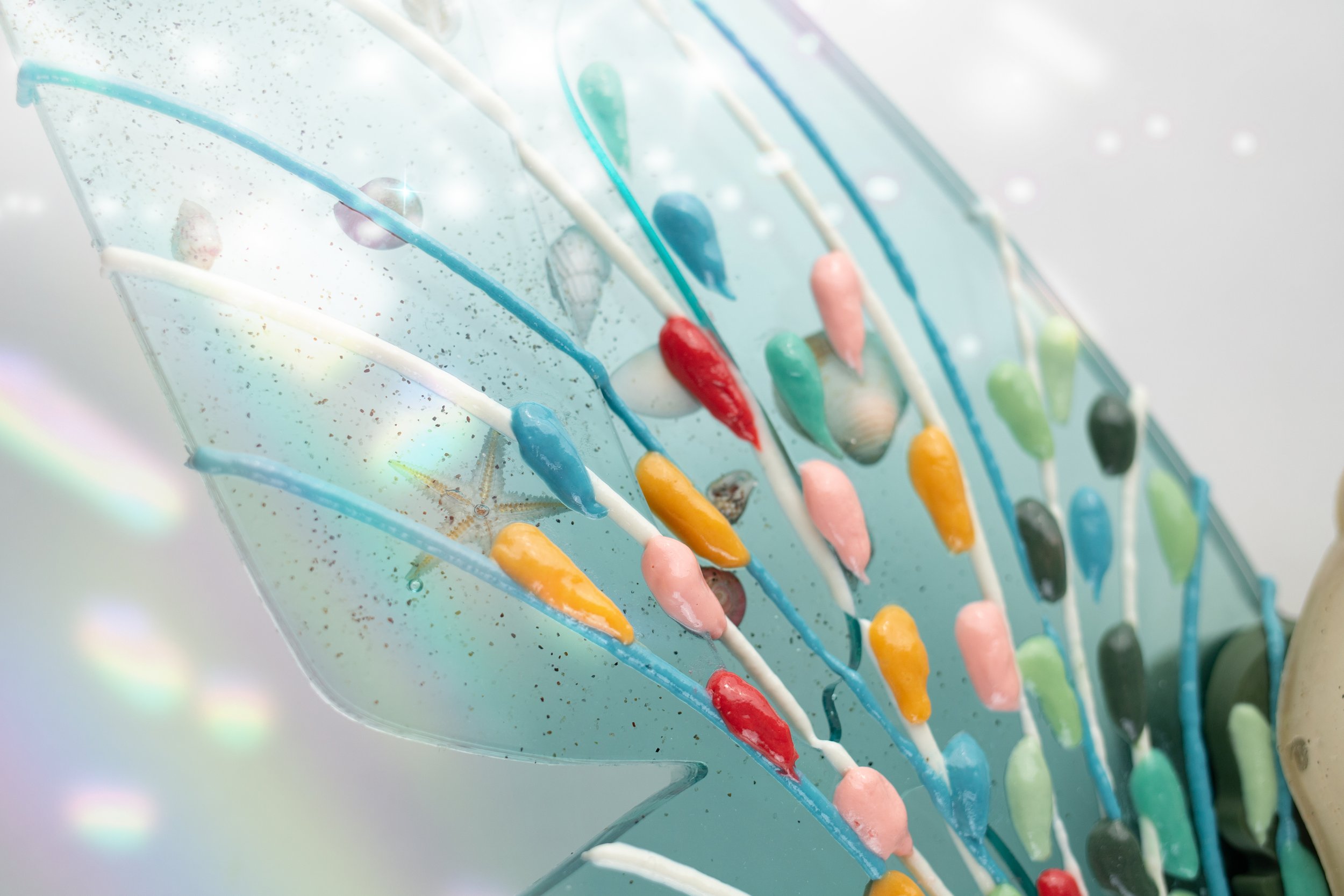 Close-up of a transparent surface, with candy-like resin, showcasing a variety of bright colors including red, yellow, green, pink, and black.