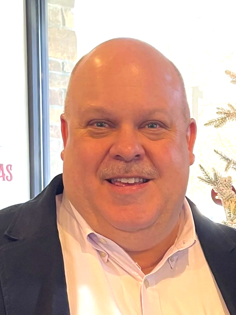 Man sitting inside a red tractor cab at a trade show.