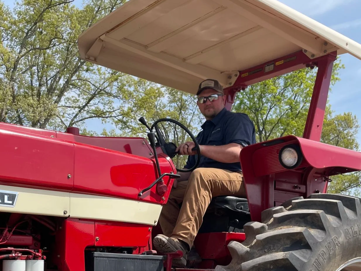 Man in overalls standing by a fence on a snowy farm