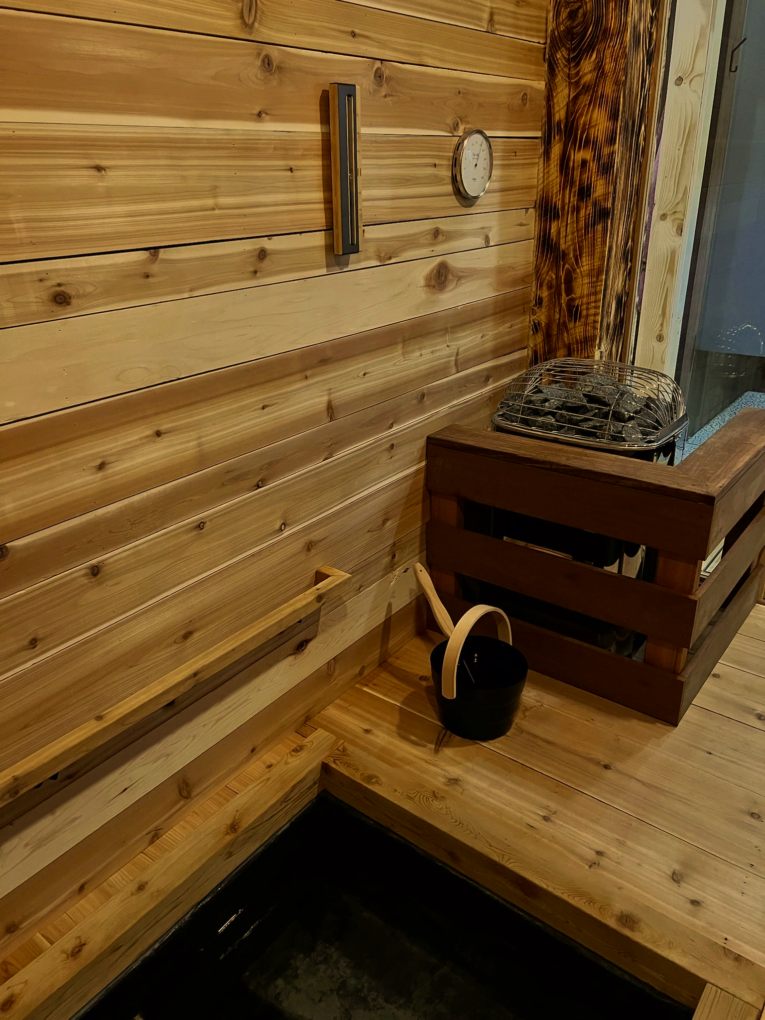 Cedar ice sauna interior with stone heater and traditional wooden ladle at Nordic on Nine spa in New Windsor NY