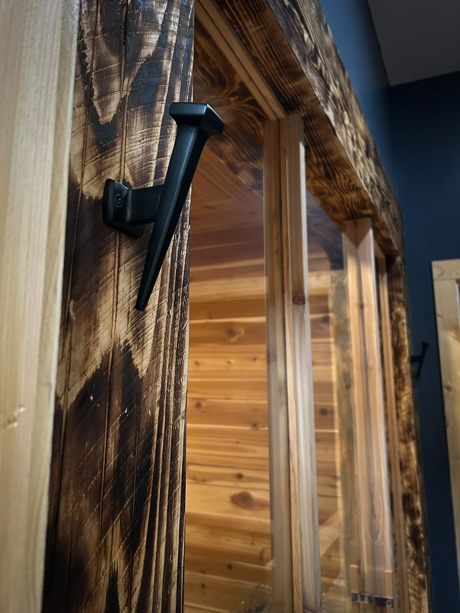 Charred wood sauna entrance with glass door revealing warm cedar interior at Nordic on Nine in New Windsor NY