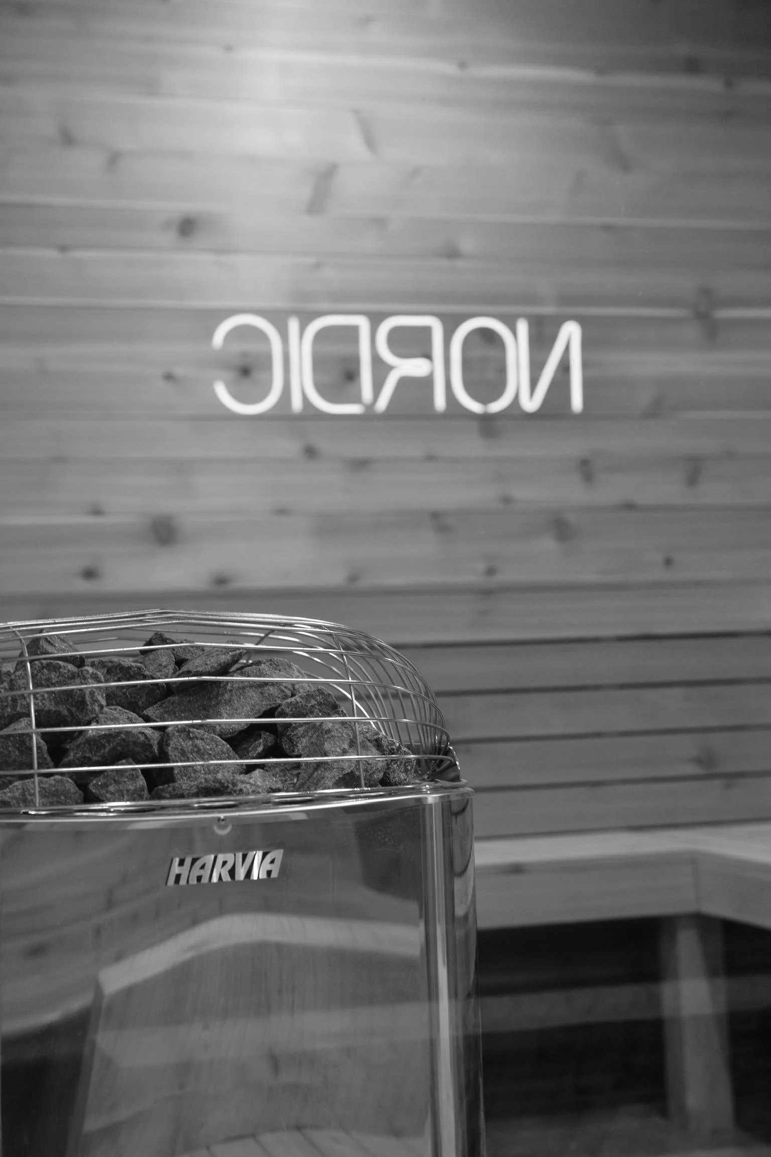 Harvia stone sauna heater with Nordic neon sign reflected in cedar sauna room at Nordic on Nine in New Windsor NY