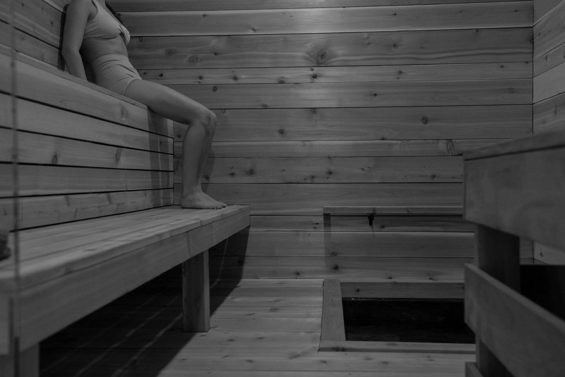 Woman relaxing on cedar bench inside the ice sauna at Nordic on Nine wellness spa in Hudson Valley NY