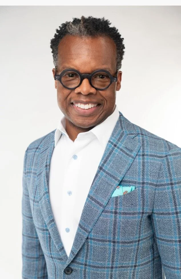 Smiling person wearing glasses and a checkered blazer