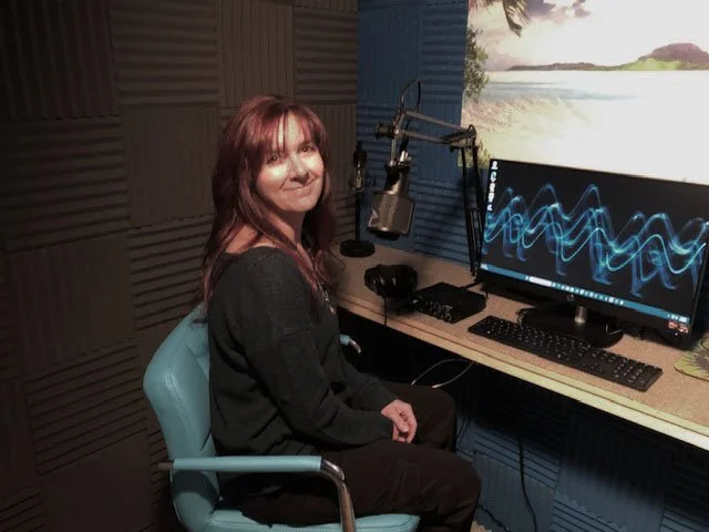 Person in a recording studio with microphone and computer