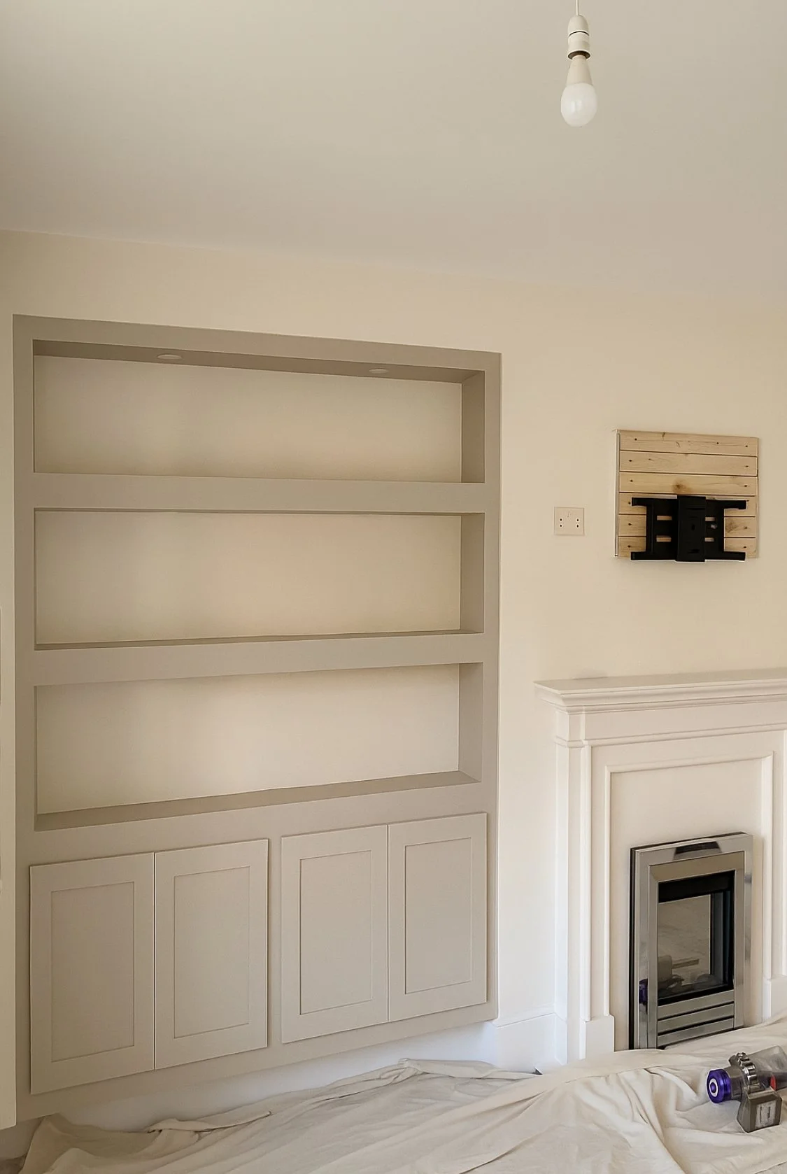Living room with built-in bookshelf, fireplace, and wall art with black shelves on a wooden panel.