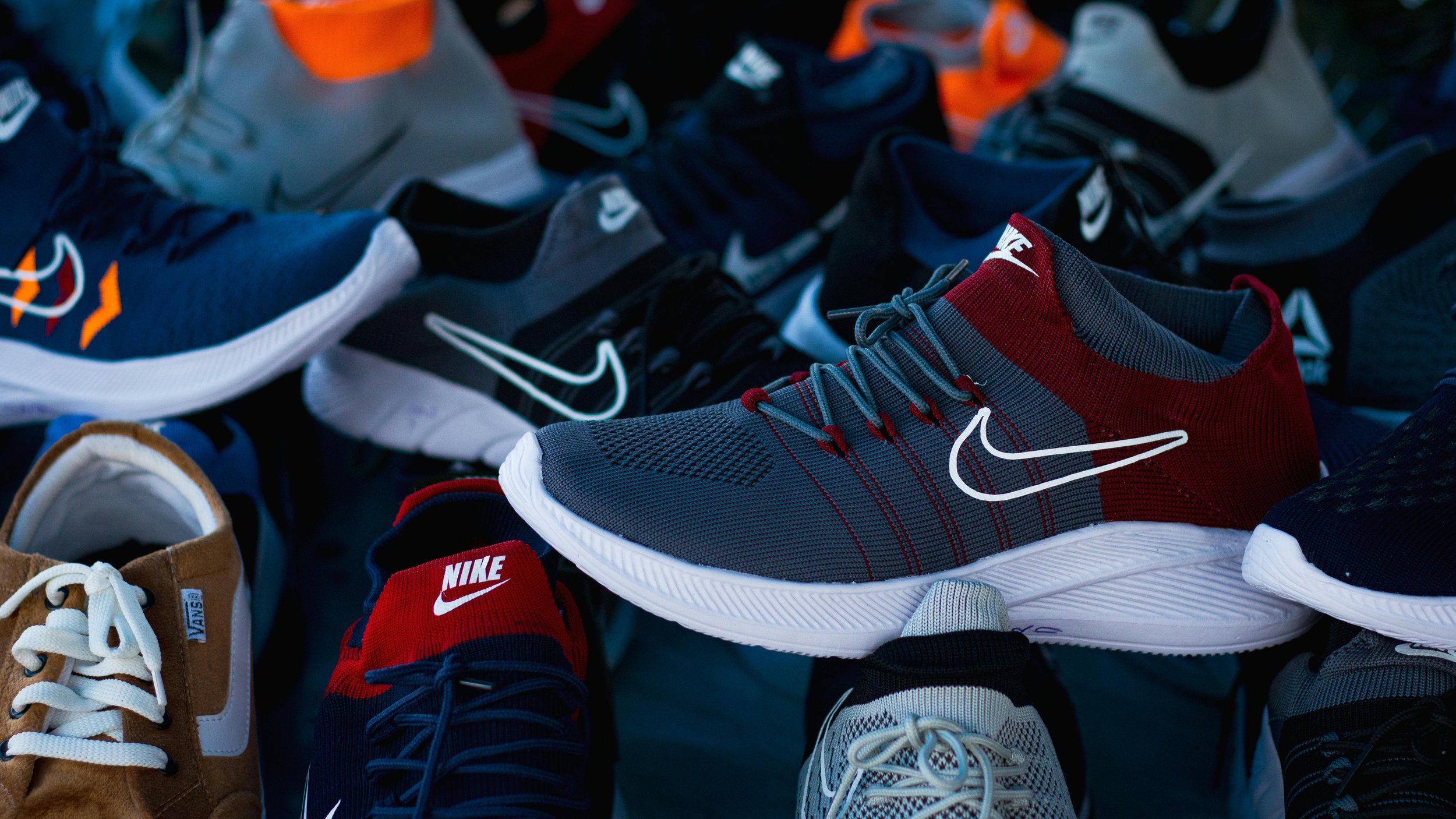 A collection of various athletic shoes placed together, including brands like Nike, Adidas, and Vans, with different colors and styles.