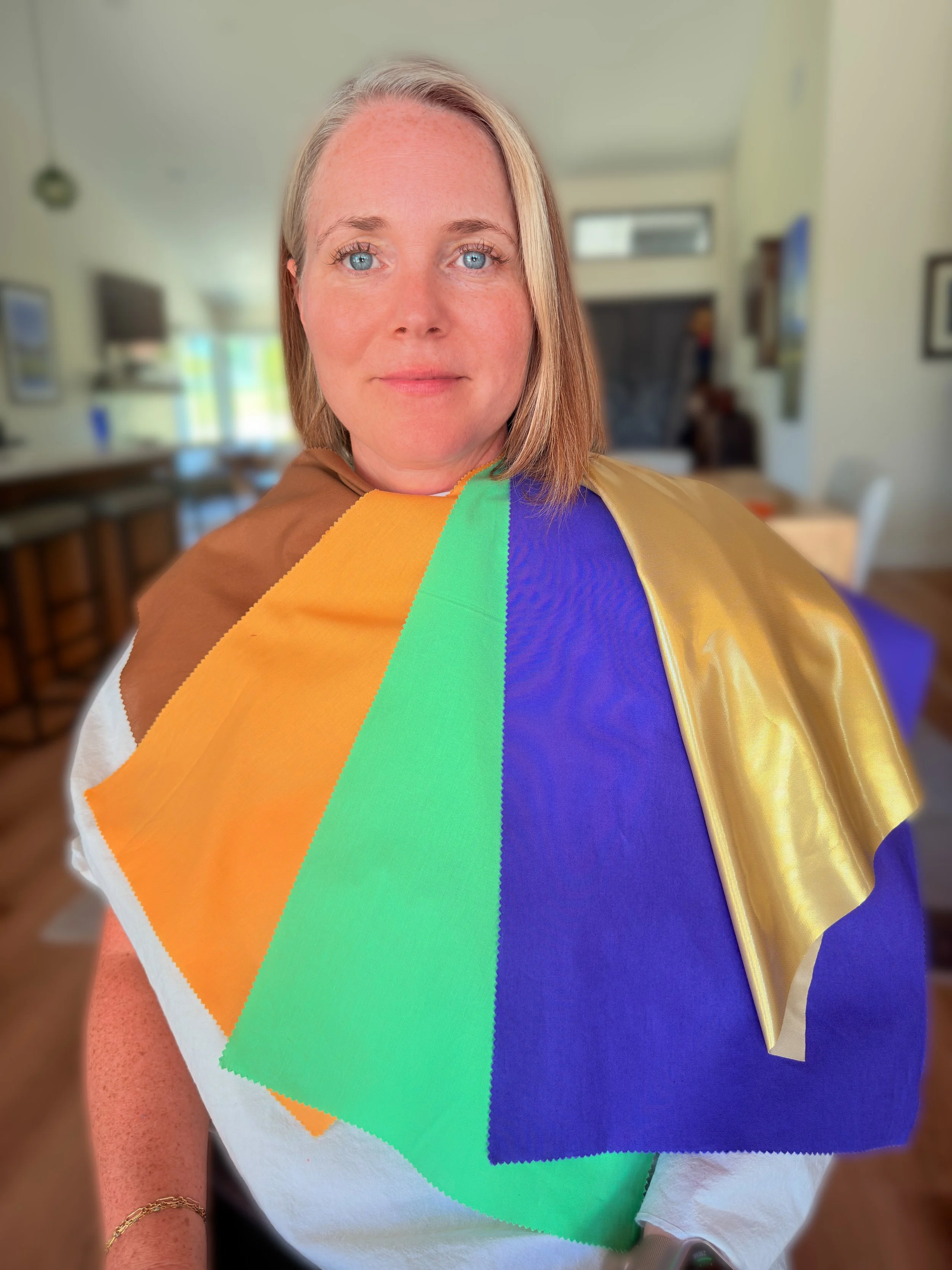 A woman with blonde hair and blue eyes wearing color analysis drapes after her color analysis session