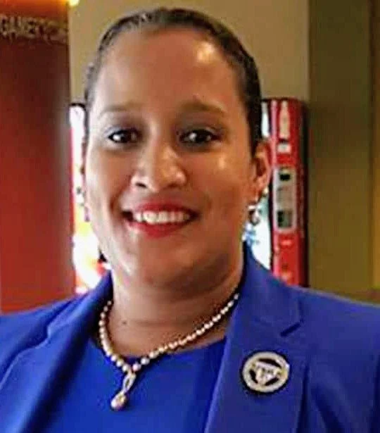 Close-up of a cheerful woman with a Blue suit on, pearl necklace, with red lipstick on and smiling