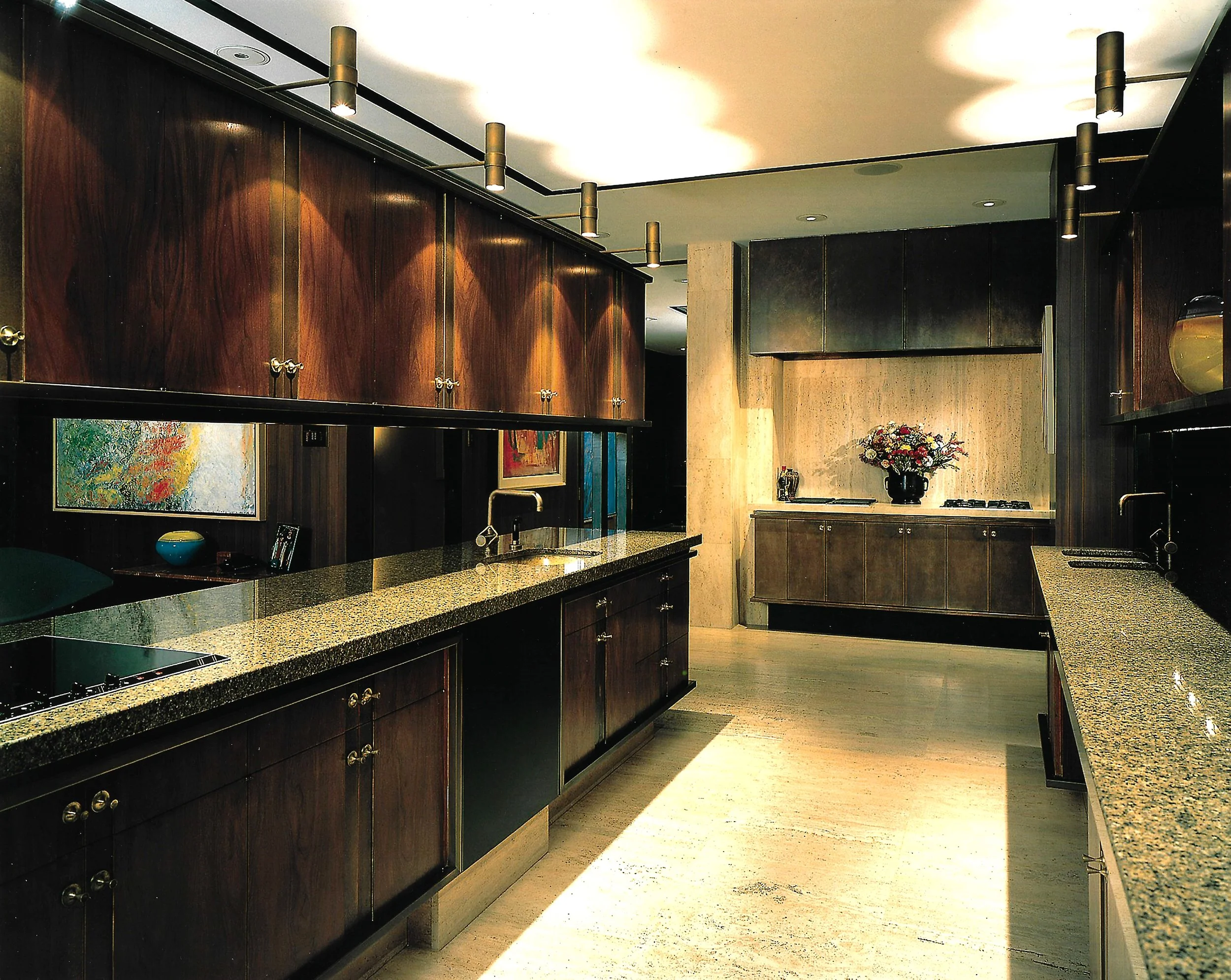 Modern kitchen with wooden cabinets, granite countertops, recessed lighting, and decorative artworks.