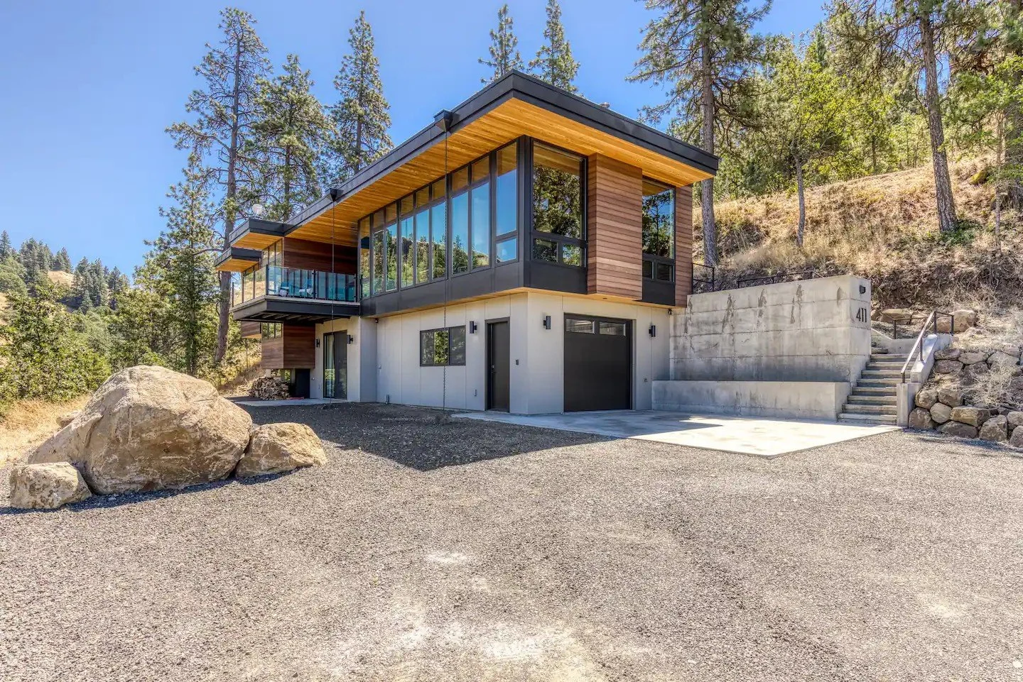 Modern house with large windows in a forested area.