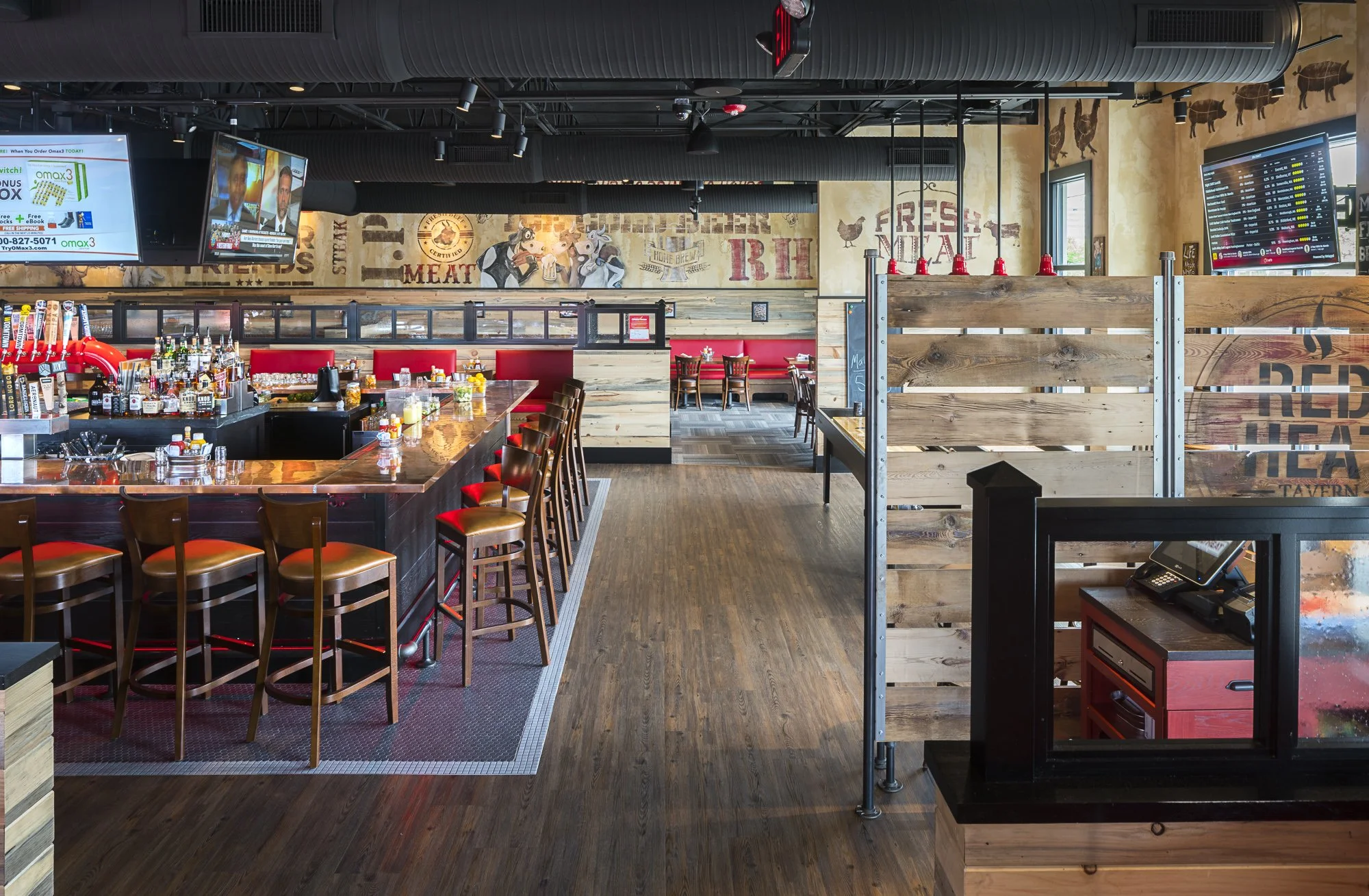 Interior of a bar and restaurant with wooden floors, a long bar counter with stools, beer taps, wall decor featuring "Meat" and "Fresh" signage, and wooden dividers.