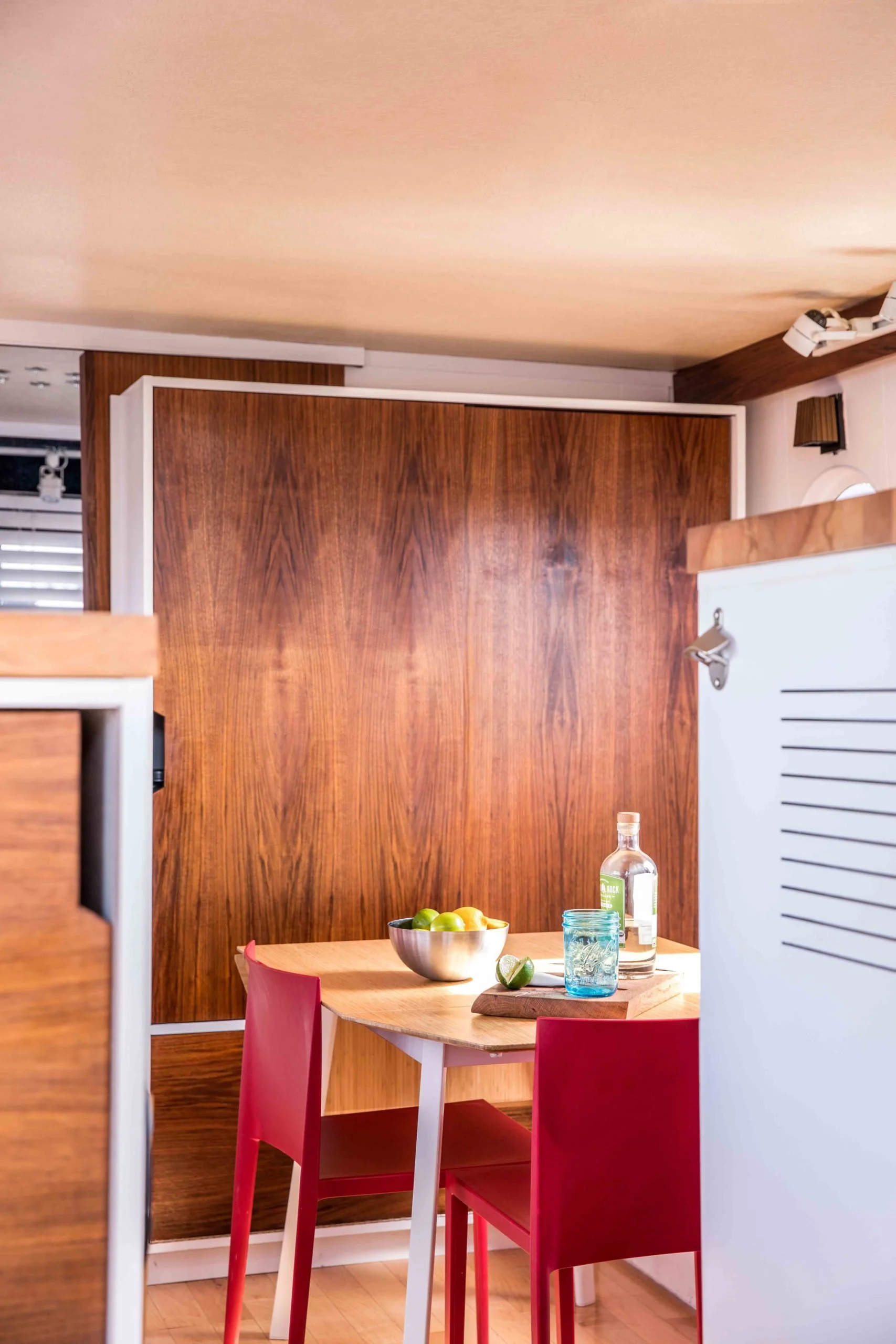 Boat interior with wooden furniture, dining table, red chairs, and kitchen items.