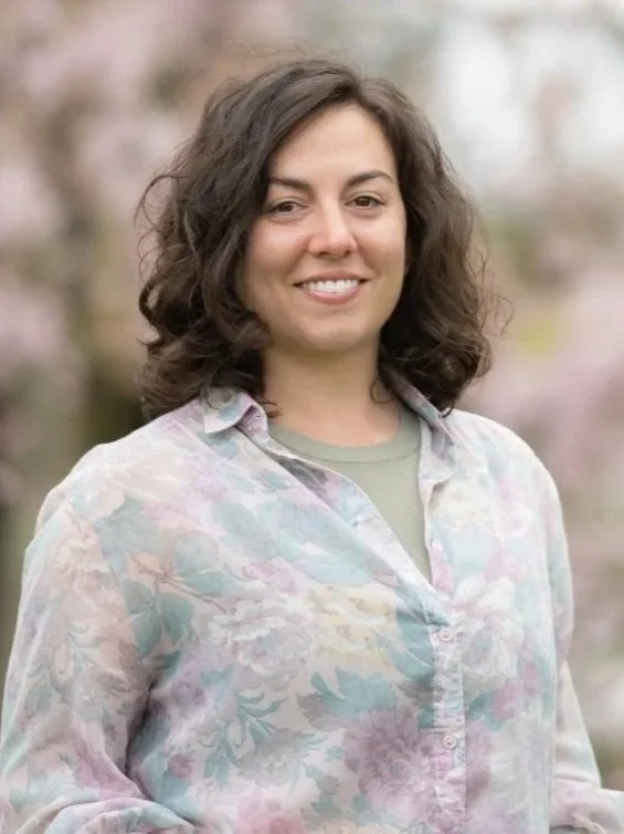 Smiling young woman standing in front of an open car trunk, wearing a rescue t-shirt.