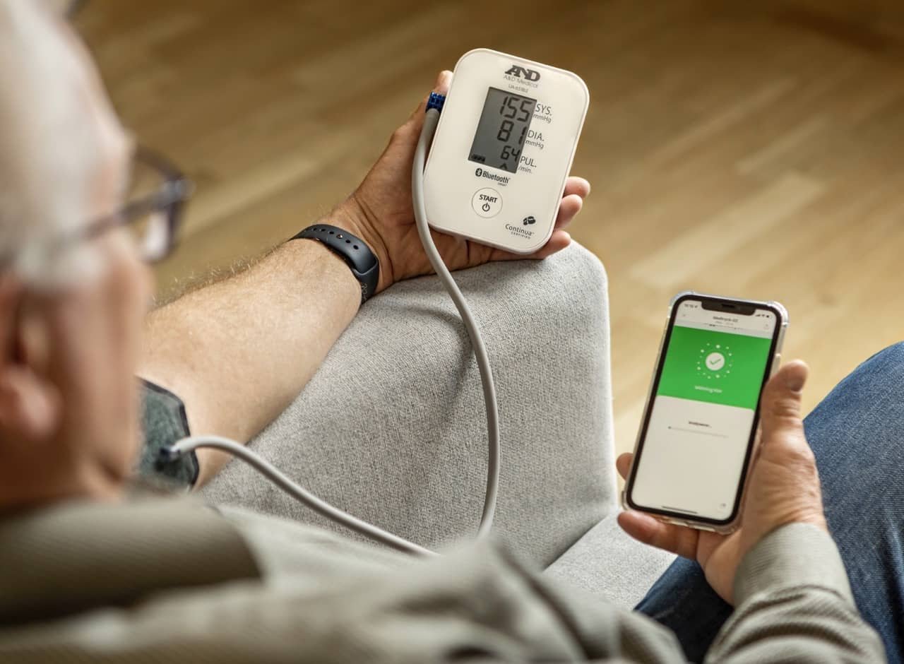 Äldre man som mäter blodtrycket på sig själv.