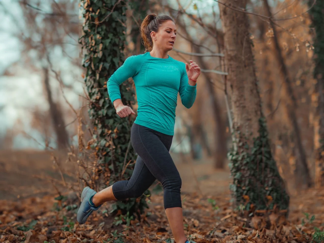 Kvinna som joggar i en skog.