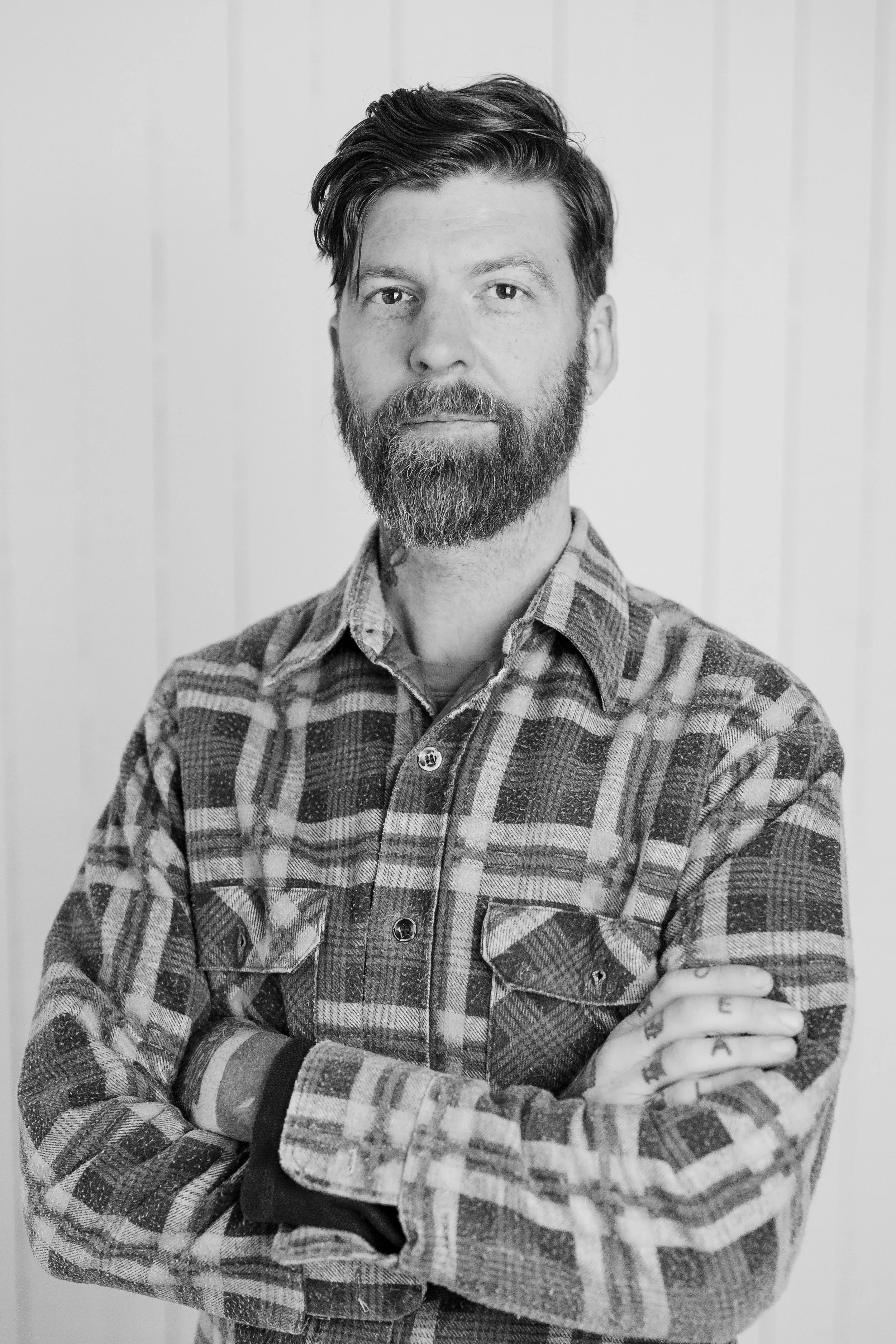 Man wearing a cap and gray sweatshirt with a logo reading 'CLARKBUILT.NET', standing in front of a textured, weathered wall.