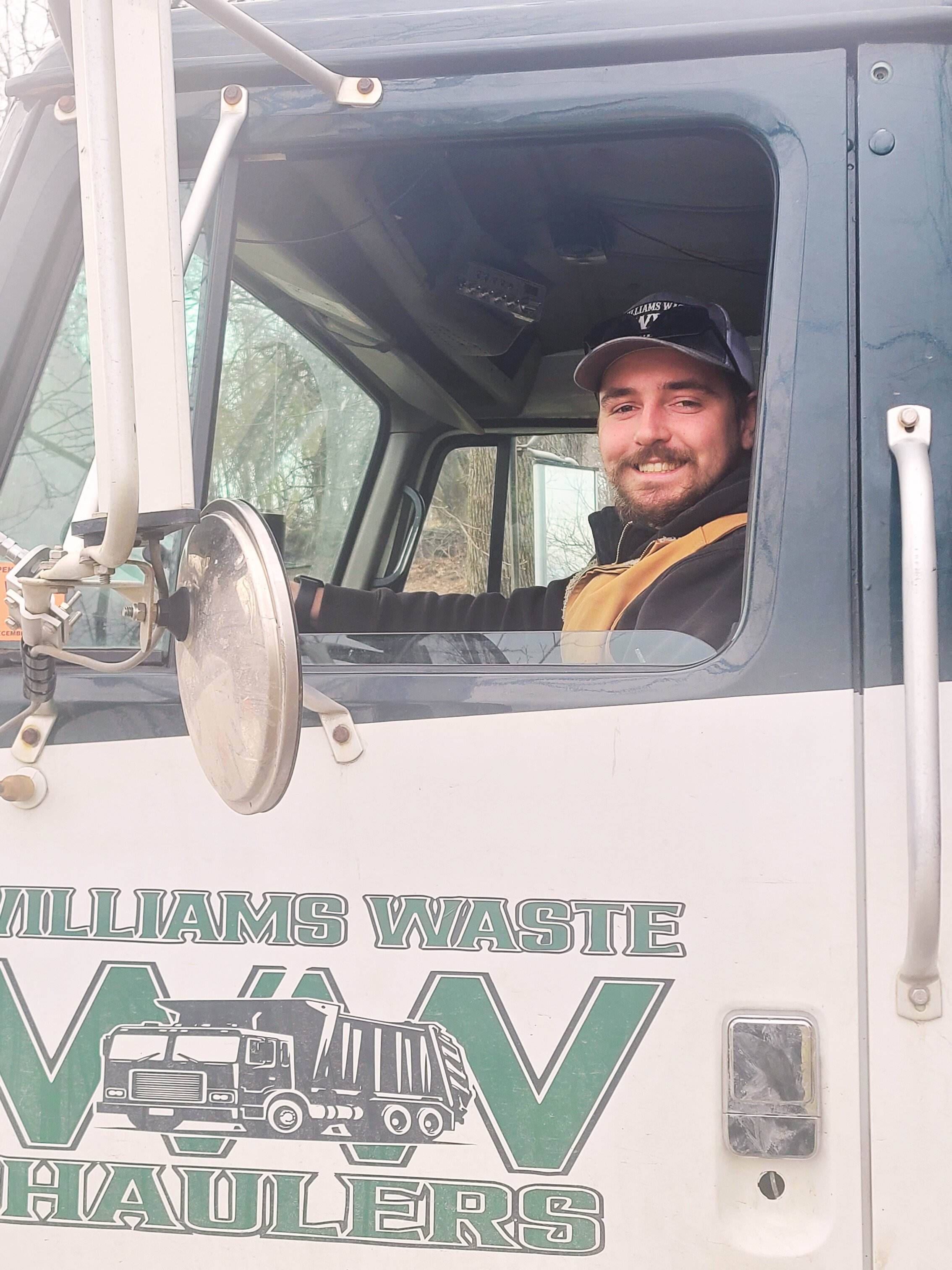 Ethan, managing partner of Williams Waste Haulers, smiling in a garbage truck in Lewisburg PA