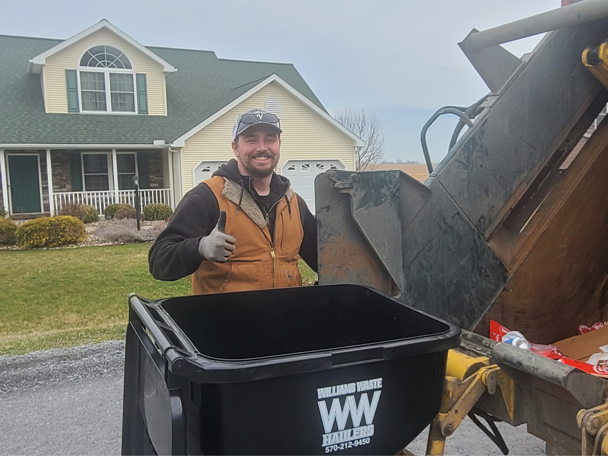 Ethan from Williams Waste Haulers loading a residential trash bin into a garbage truck in Lewisburg PA