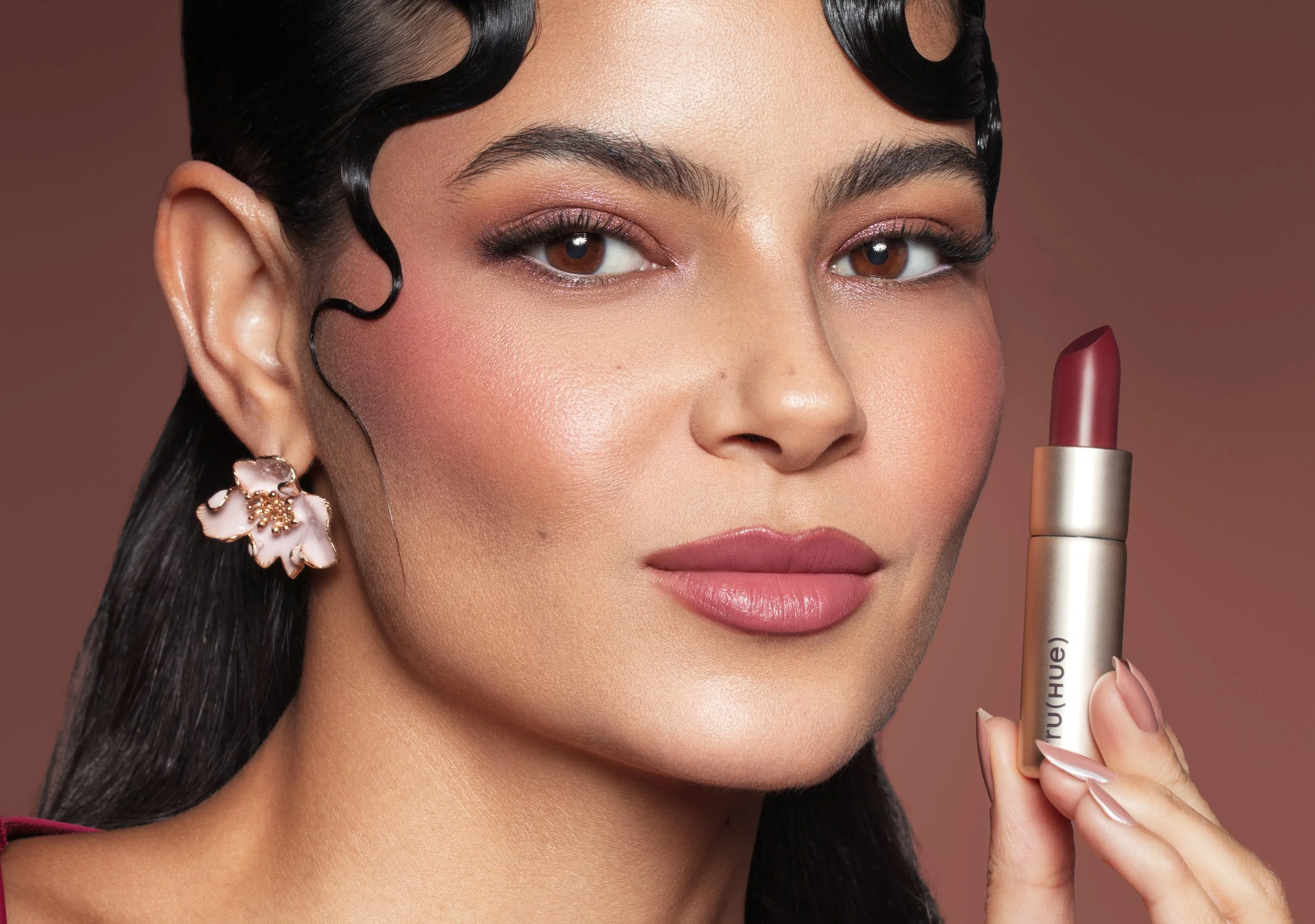 Model holding TRU(HUE) lipstick, featuring beauty campaign photography and product packaging design.