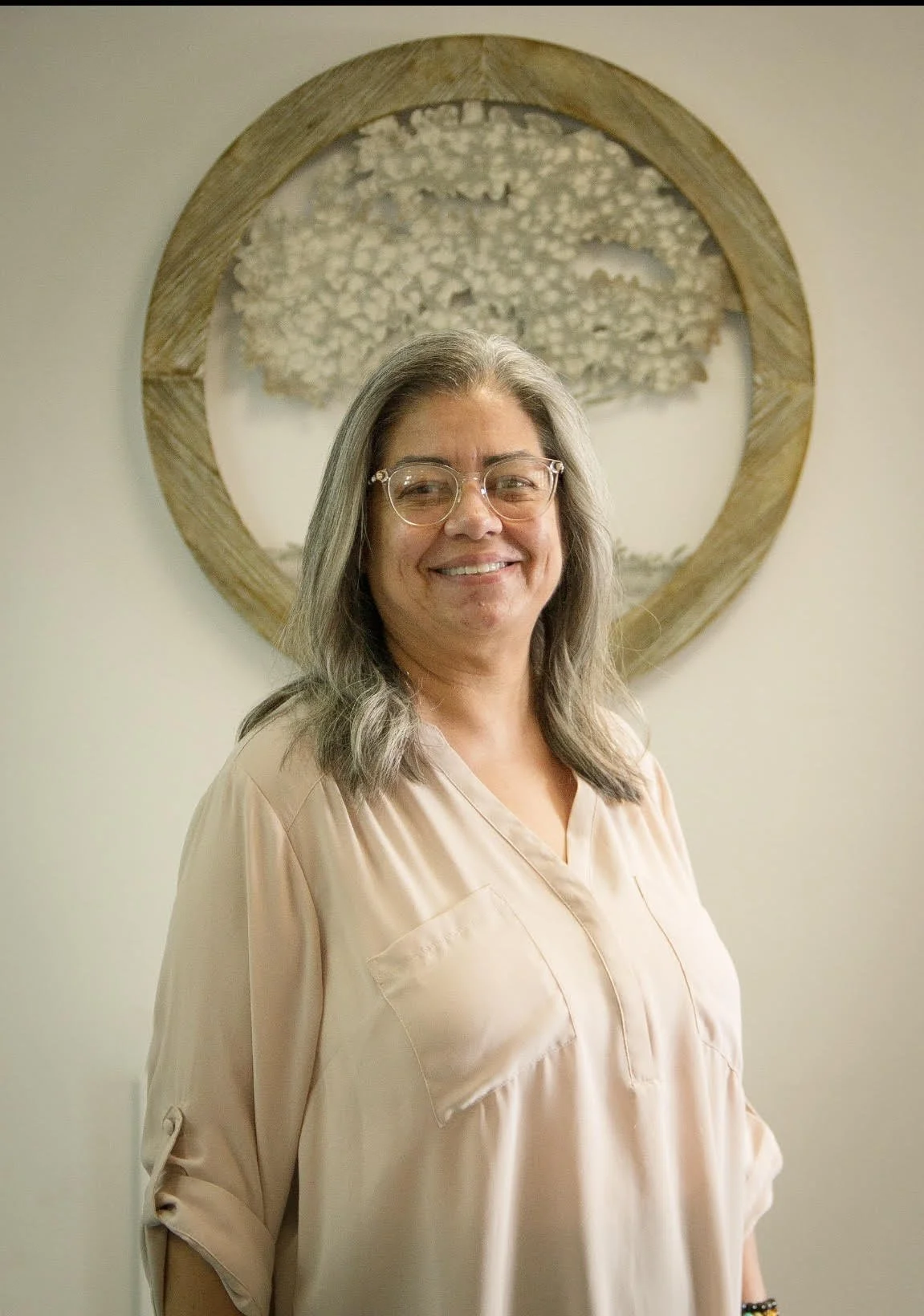 Bust shot of Micki Jaramillo holding an image of the Self Help Center logo
